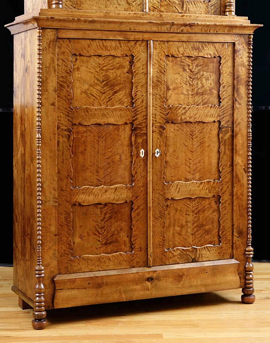 This North German Biedermeier cabinet has an unusual form with very handsome features. The beautiful grain offered by fire birch lends some drama, making this piece a wonderful focal point in any room, in addition to offering ample storage for