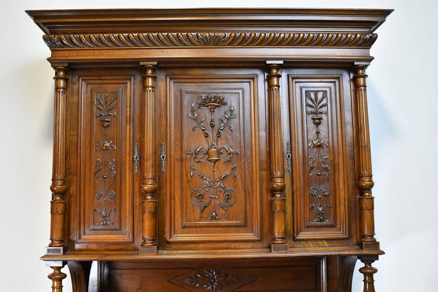 A Belle Époque French buffet a deux corps in a medium, brown-colored walnut. This very beautiful Renaissance-style buffet features exceptional carvings of urns, flowers & foliage that are carved directly from the solid walnut panels (not applied),