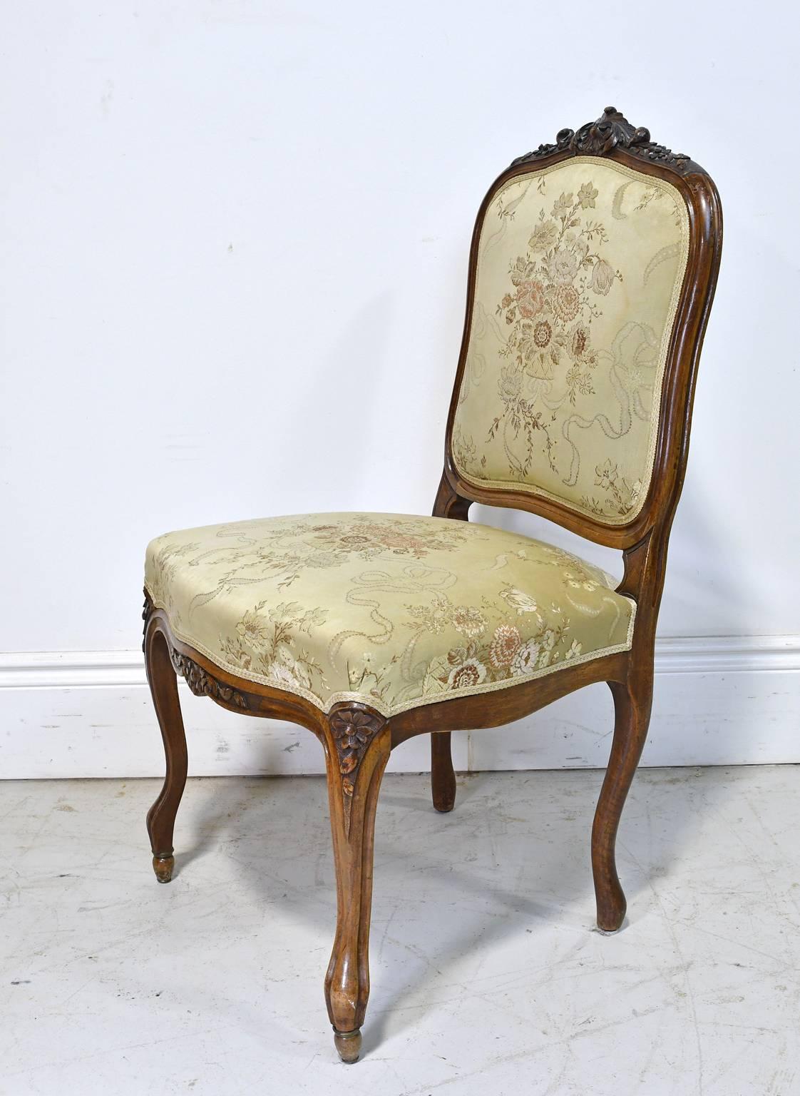 Une très belle chaise de style Louis XV avec une structure en noyer et un siège et un dossier rembourrés. Il présente des sculptures de festons et de feuillages le long de la crête arrière, des fleurs sculptées le long du tablier et sur les genoux