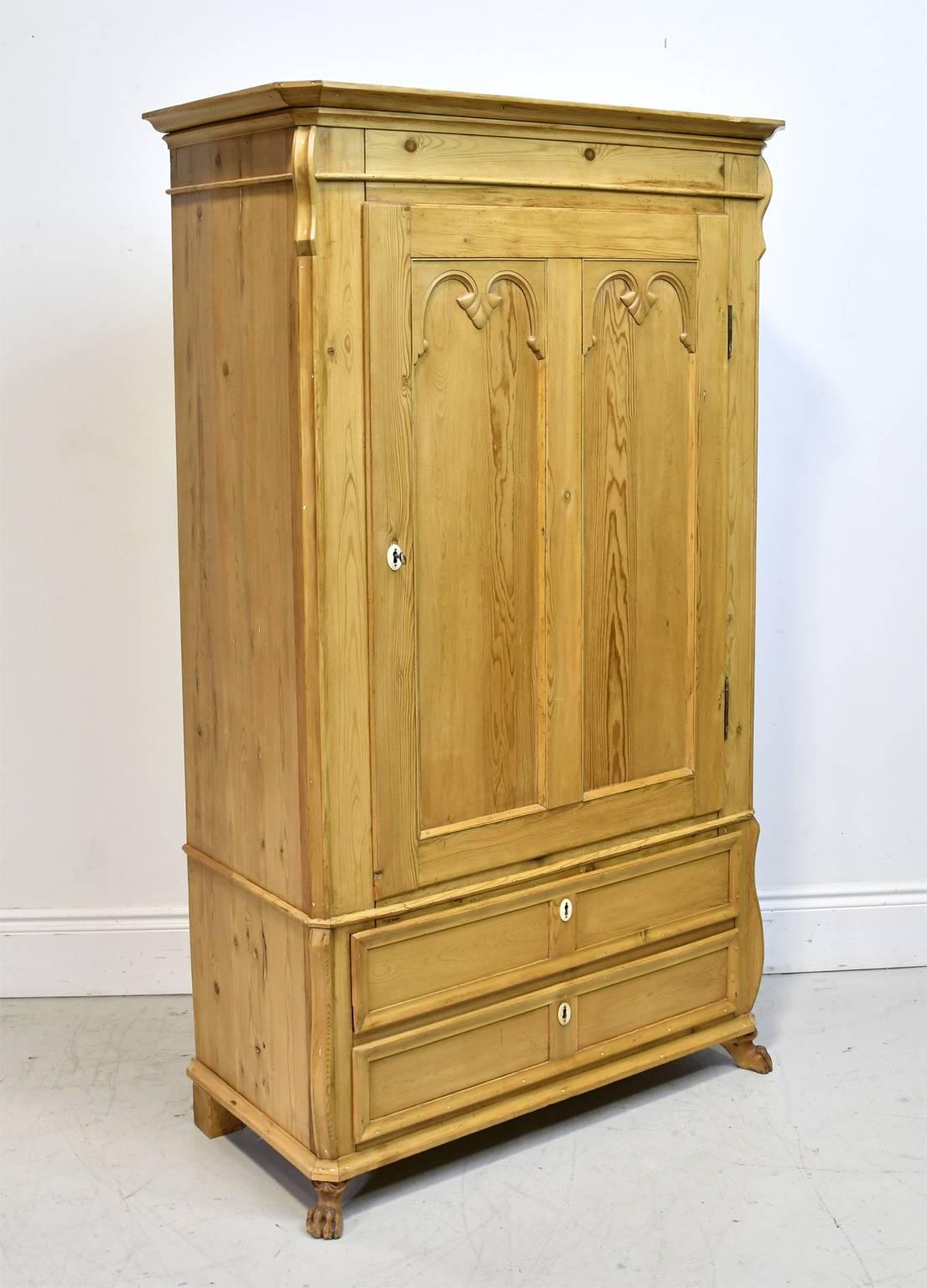 A charming Scandinavian country armoire in a light, honey-colored pine with one cabinet door opening to 3 interior, adjustable shelves, with two exterior bottom drawers. Denmark, circa 1835. Embellishments include two panels with double arches on