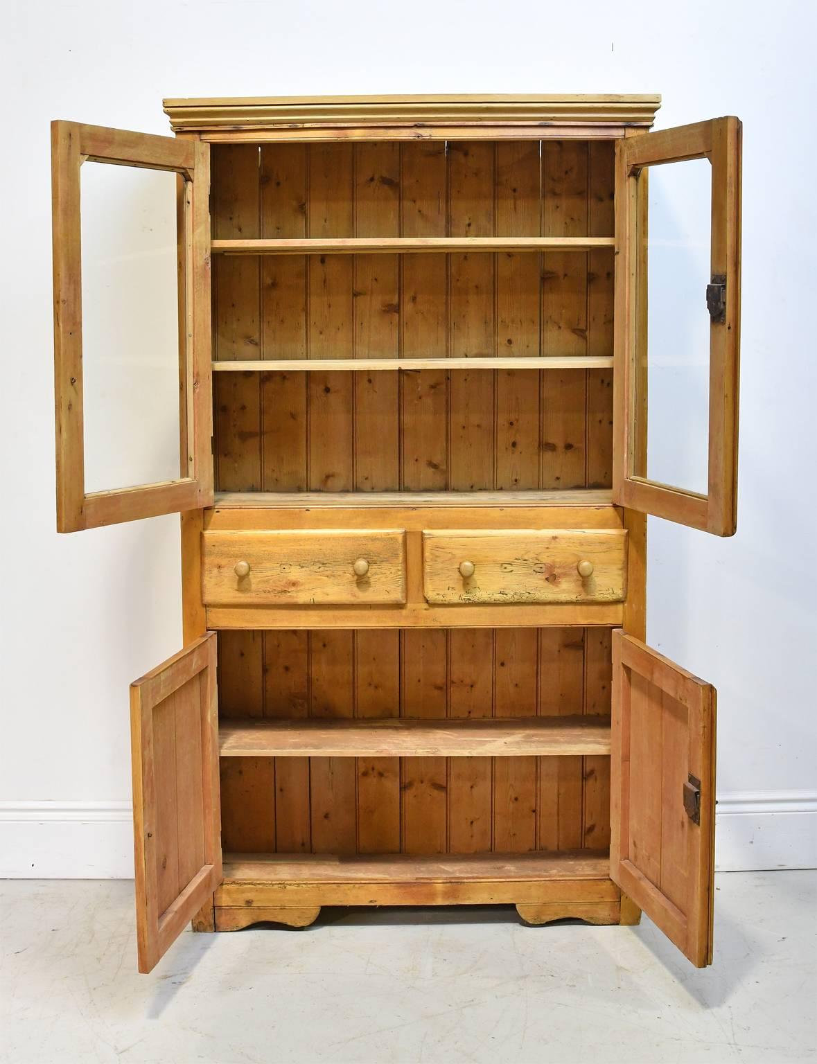 A very shallow pine cupboard with two glazed doors & two paneled wood doors divided by a set of drawers. A charming piece for toys, books, towels or liquor! England or Scotland, circa mid 1800's.
44 3/4