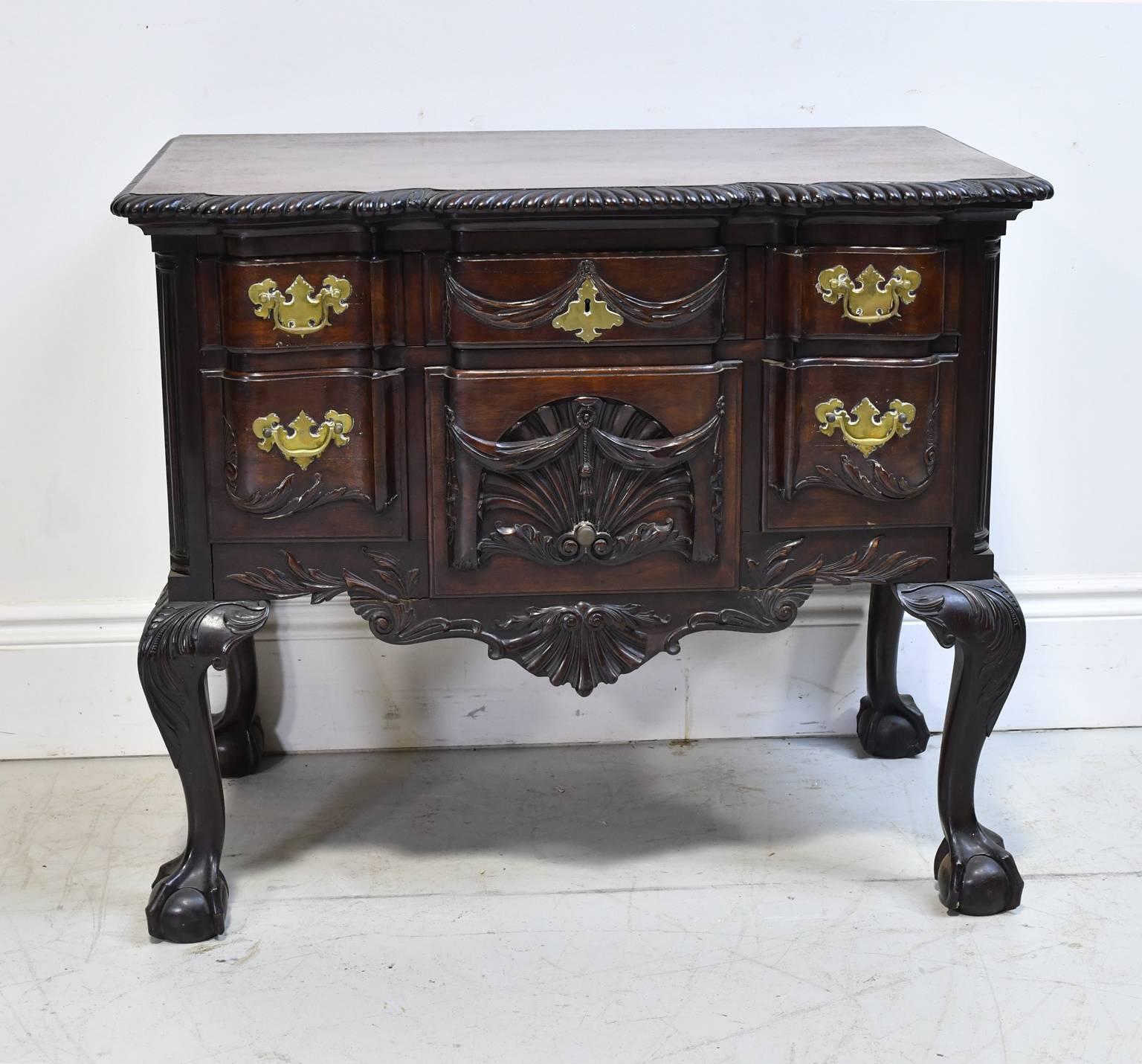 A lovely centennial lowboy chest in mahogany in the Chippendale style with six drawers along blockfront, brass pulls & plates, and cabriole legs ending in ball-and-claw feet. Features beautifully-articulated carvings throughout which include