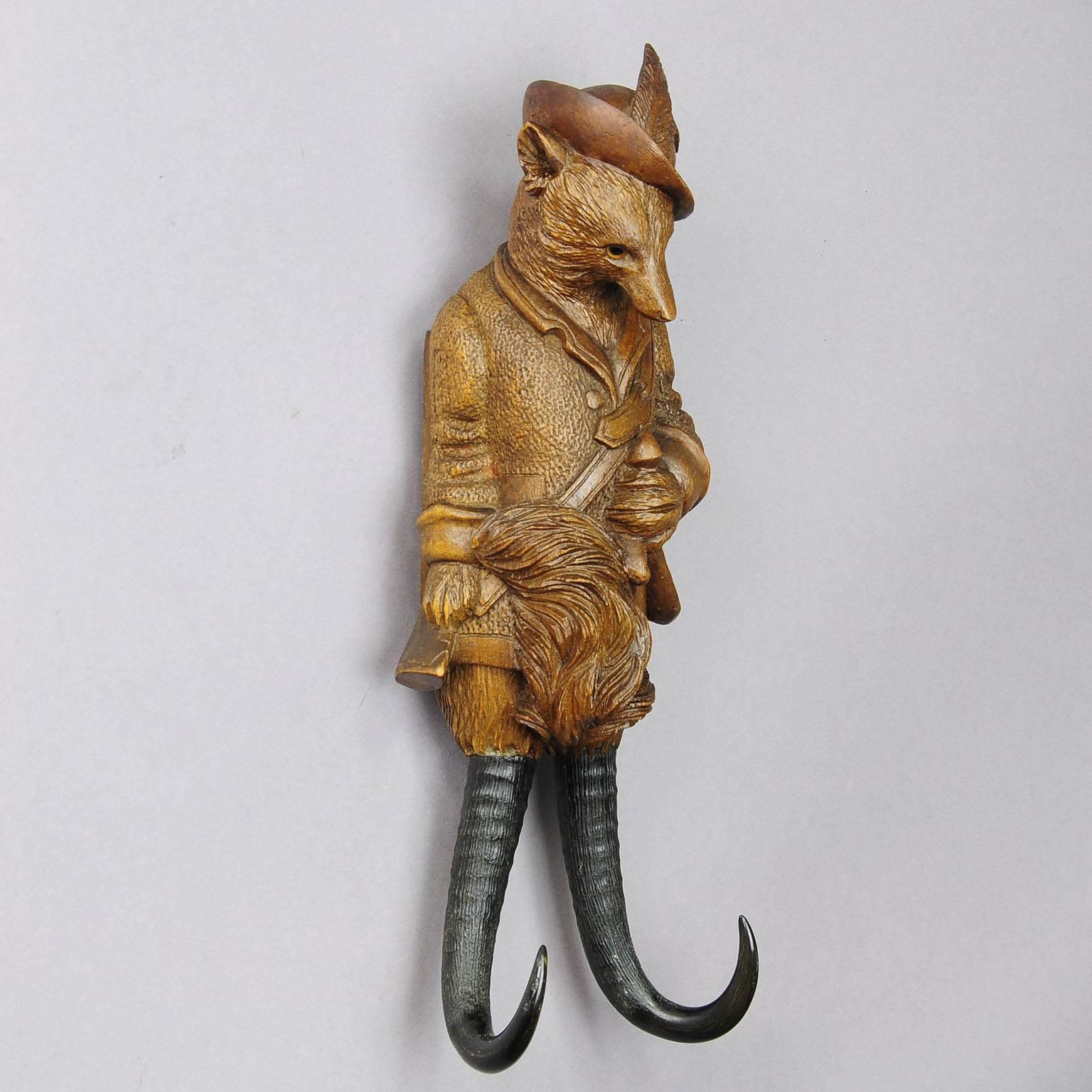 A cabin decor hand-carved hunting fox whip holder or coat rack. With music work integrated in the body which starts playing when something is hanged on the chamois horns. Playing two tunes.