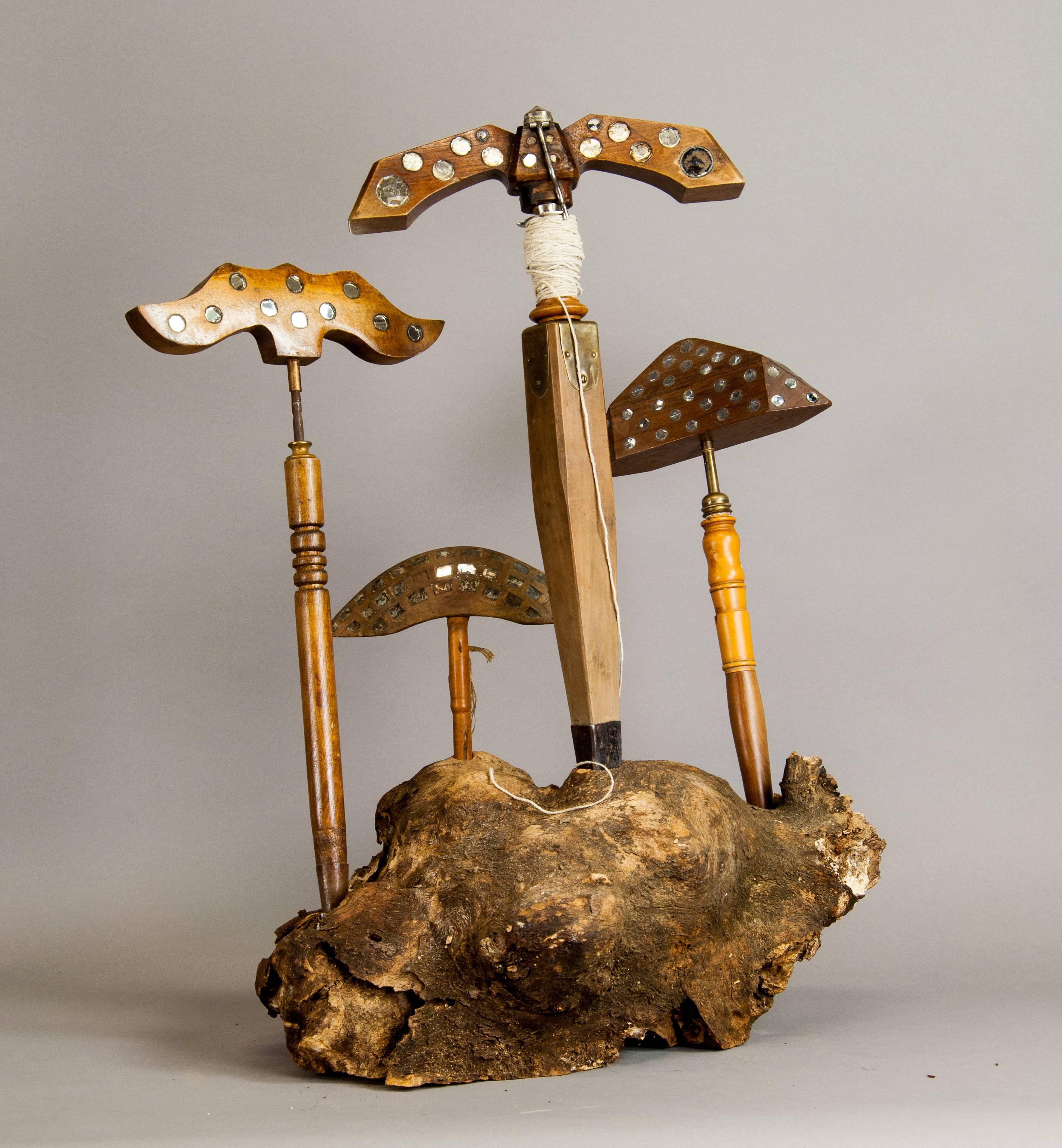 This is a set of four lark mirrors which have been used for fowling. Birds are frightened by turning the wooden piece on top of the tools. Displayed on a large piece of root wood.