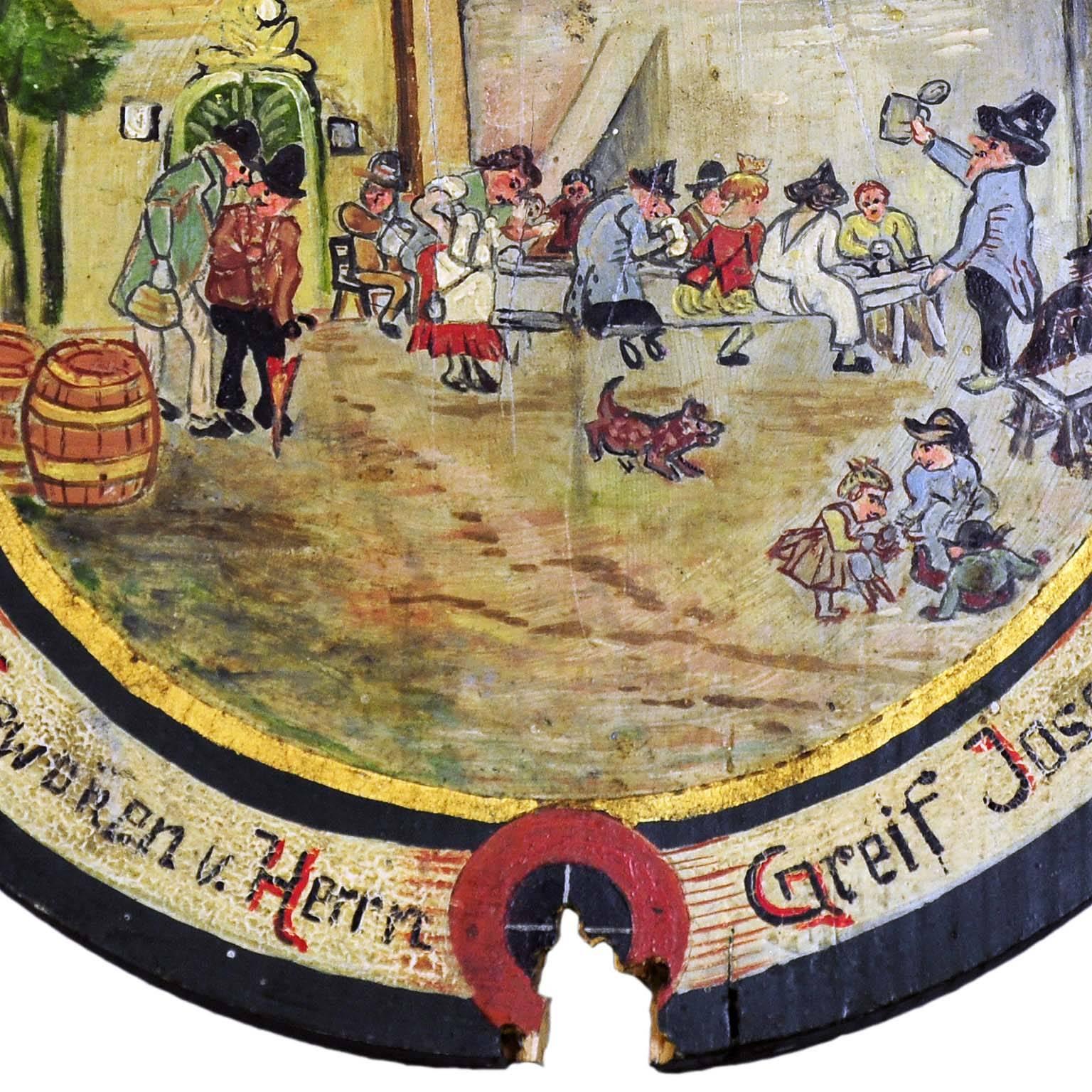 A rare hand-painted antique shooting target depicting a folksy village live scene. Oil on wood, hand-painted in naive painting style. Bavaria, circa 1920. On the base with impacts of the shooting. on the back handwritten list of the participants of