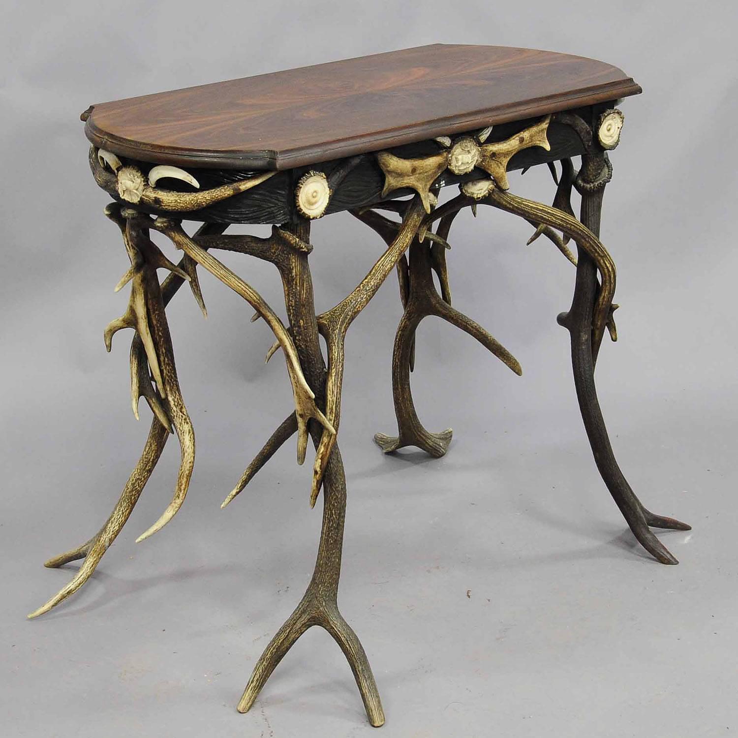 A small antique antler side table. Decorated with several antlers from the deer, fallow deer and stag. Each side with turned and carved Horn roses. Walnut top with carved border. Executed circa 1890.