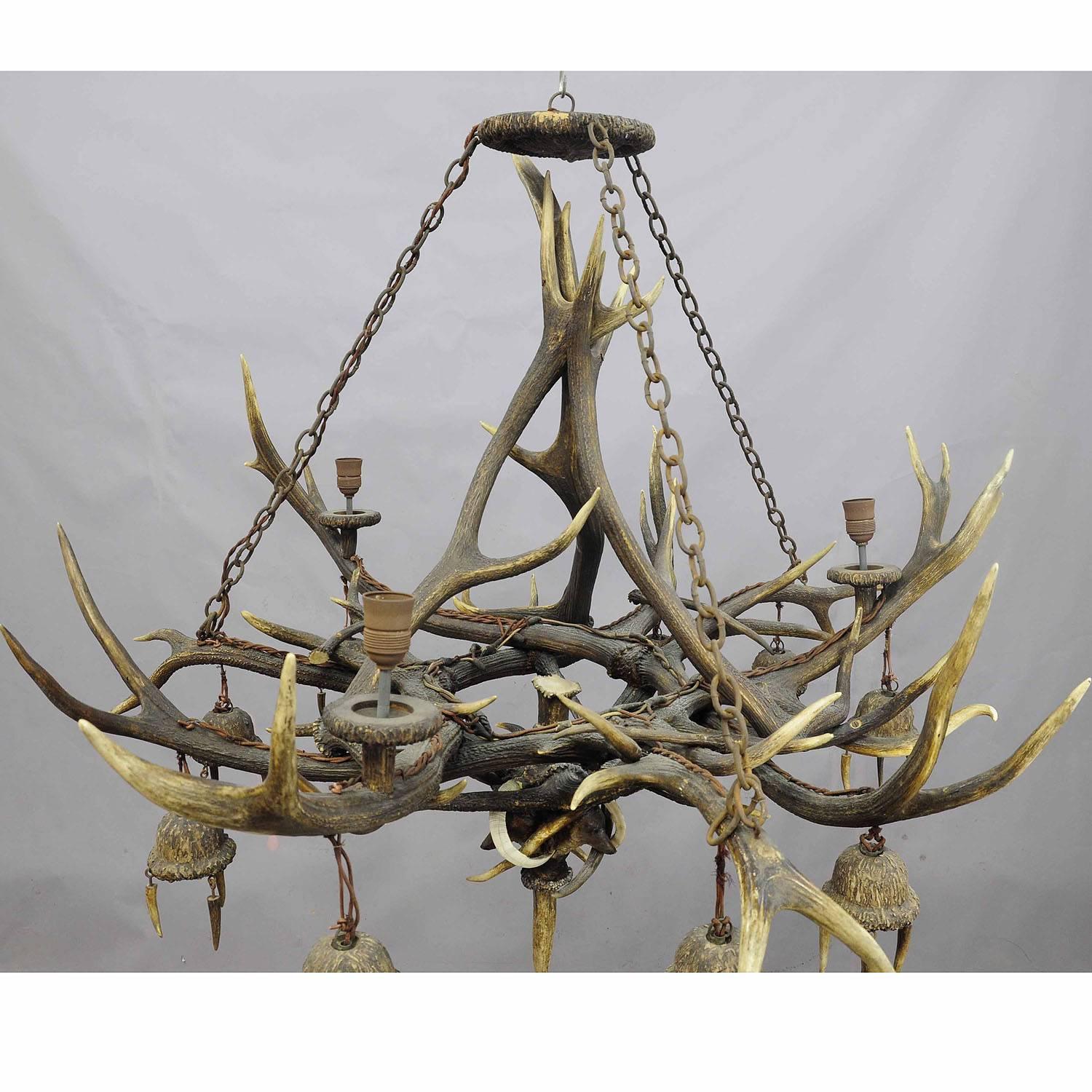 An impressive rustic antler chandelier. Manufactured from several stag and deer antlers, circa 1880. On the lower part decorated with three fox heads and wild boar tusks. Nine hanging fixtures made of wood and plaster, three fixtures on the top. A