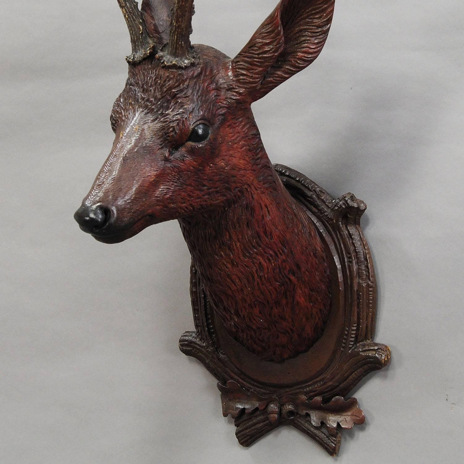 A large hand-carved wood deer head with original deer horns. Mounted on a carved wood plaque, executed, circa 1900.