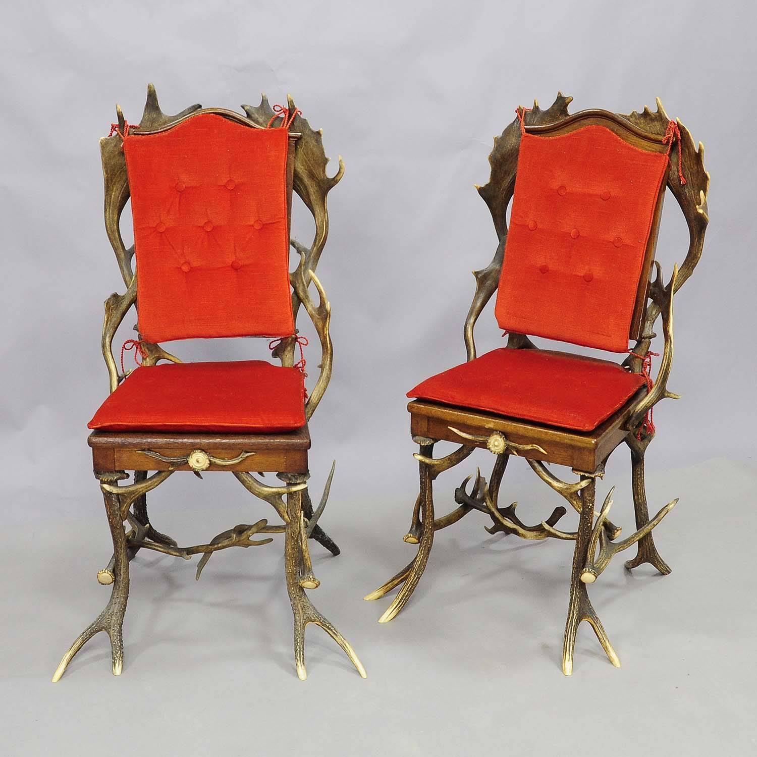 A pair antique Black Forest antler chairs with real stag antlers as legs and backrest with fallow deer antlers, seat and backrest with wicker mesh. Black Forest, circa 1900. Come with cushions with red canvas which were added later.