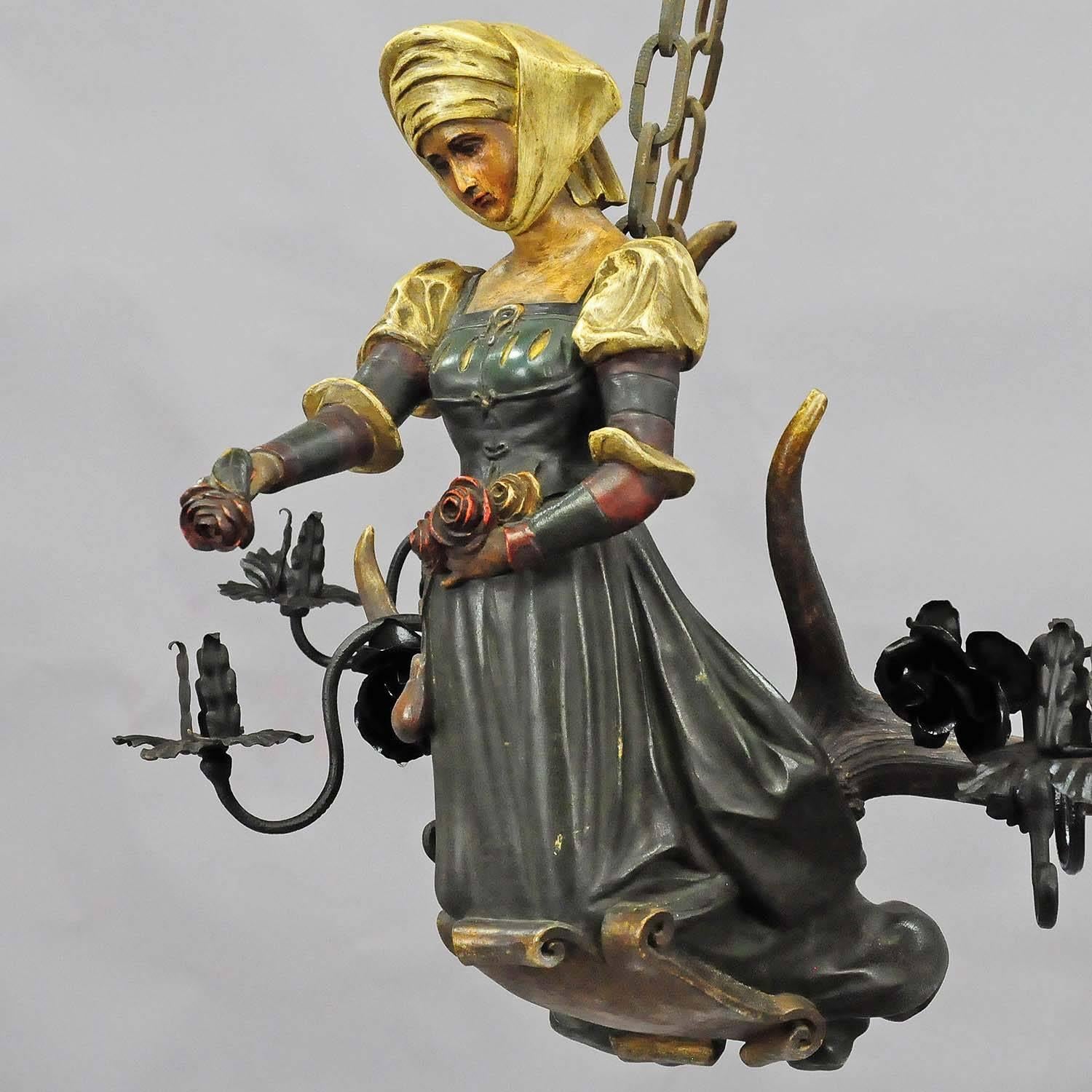 An antique lusterweibchen statue of a rose maid - made of hand-carved wood. Mounted on a pair of original fallow deer antlers with four hand-forged iron candleholders in the shape of rose blossoms. Executed circa 1890. Measures:  Height figure only