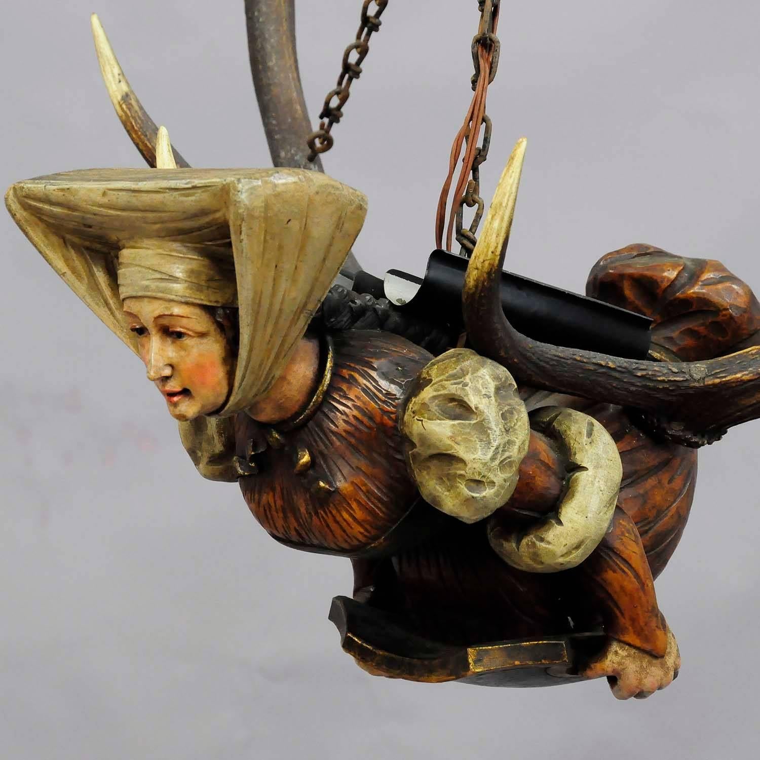 An antique lusterweibchen statue of a medieval lady - made of hand-carved and painted wood - mounted on a pair of original deer antlers with two spouts on the back of the figure (added later).