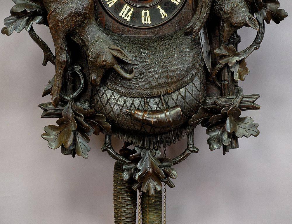 a very rare trumpeter clock. elaborate carved wooden case with chamois and fox game. clockwork with two metal trumpets. overhauled by clockmaker -  in working order. a very rare original piece of black forest clock making.