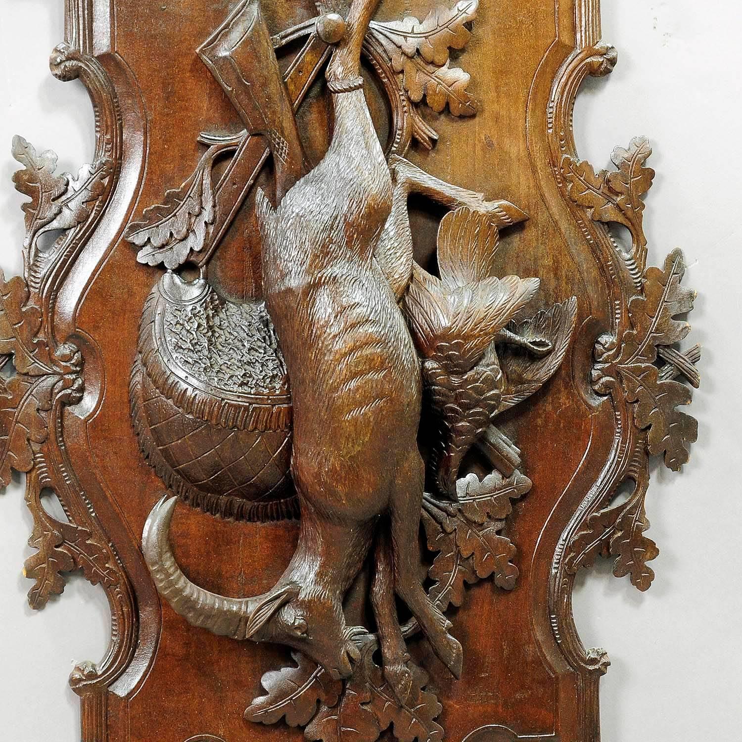 An antique wooden hunting wall plaque with impressive carvings of ibex, pheasant and game bag. Black Forest, executed circa 1900.

Measure: width 15.75