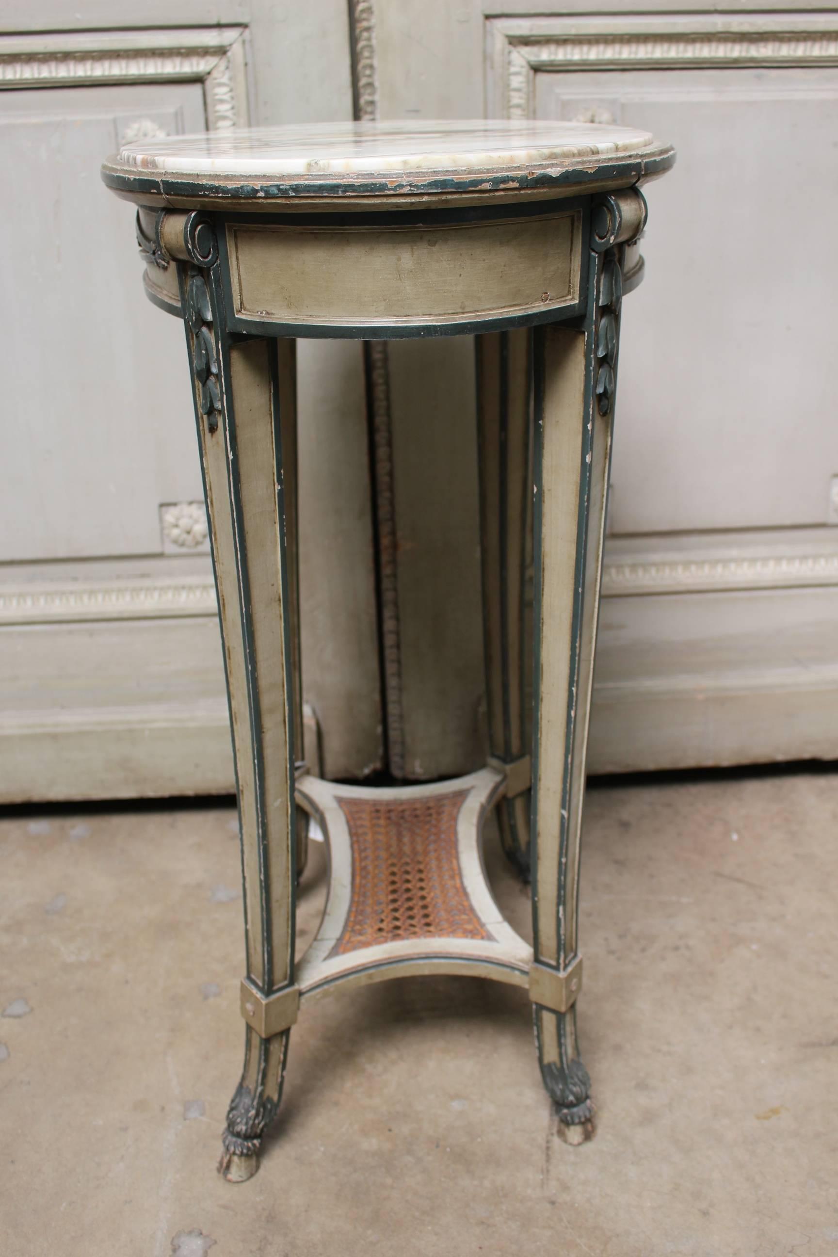 A French Directoire style painted wood table with marble top and caned shelf.