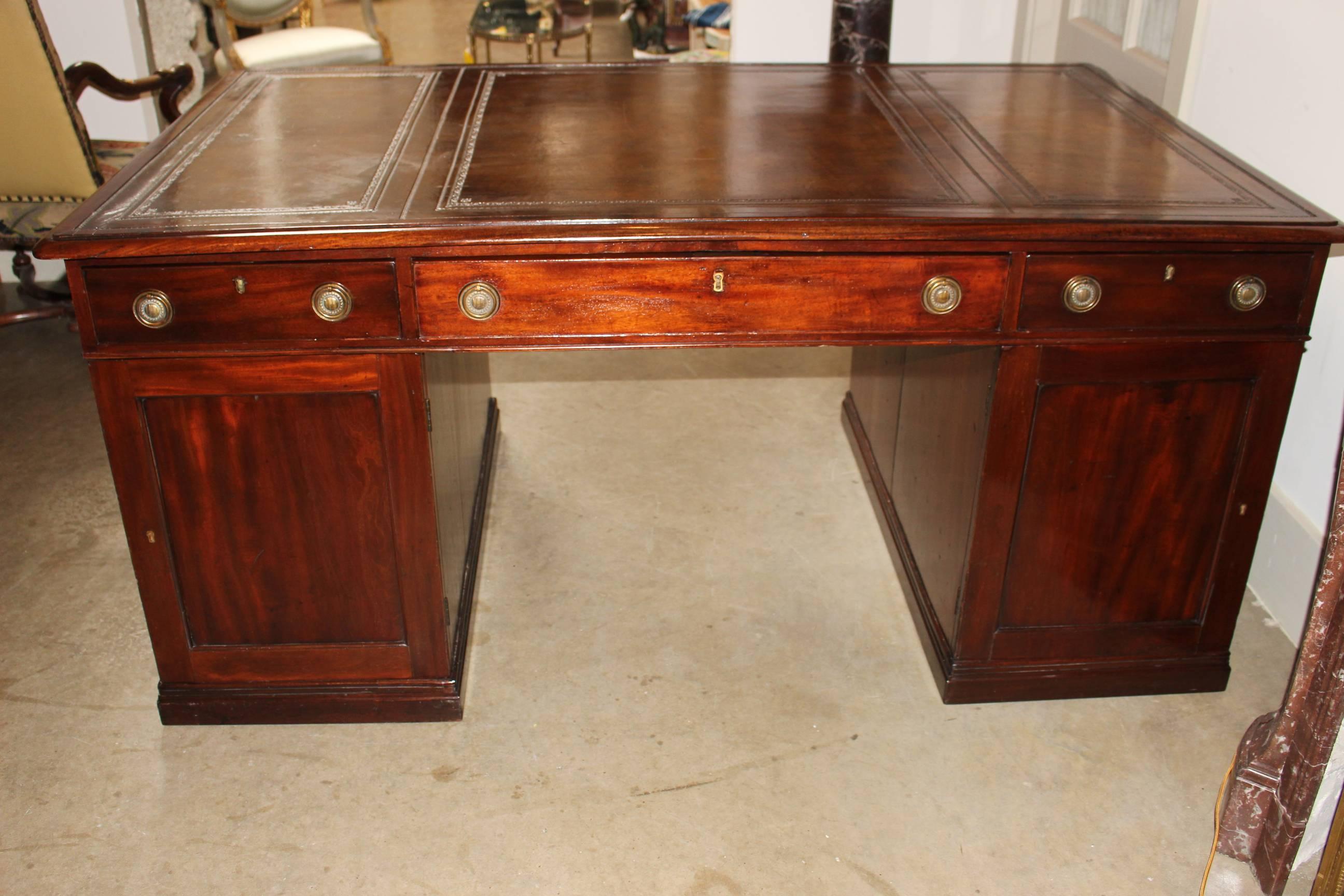An English Regency mahogany partner's desk with leather top and brass pulls.