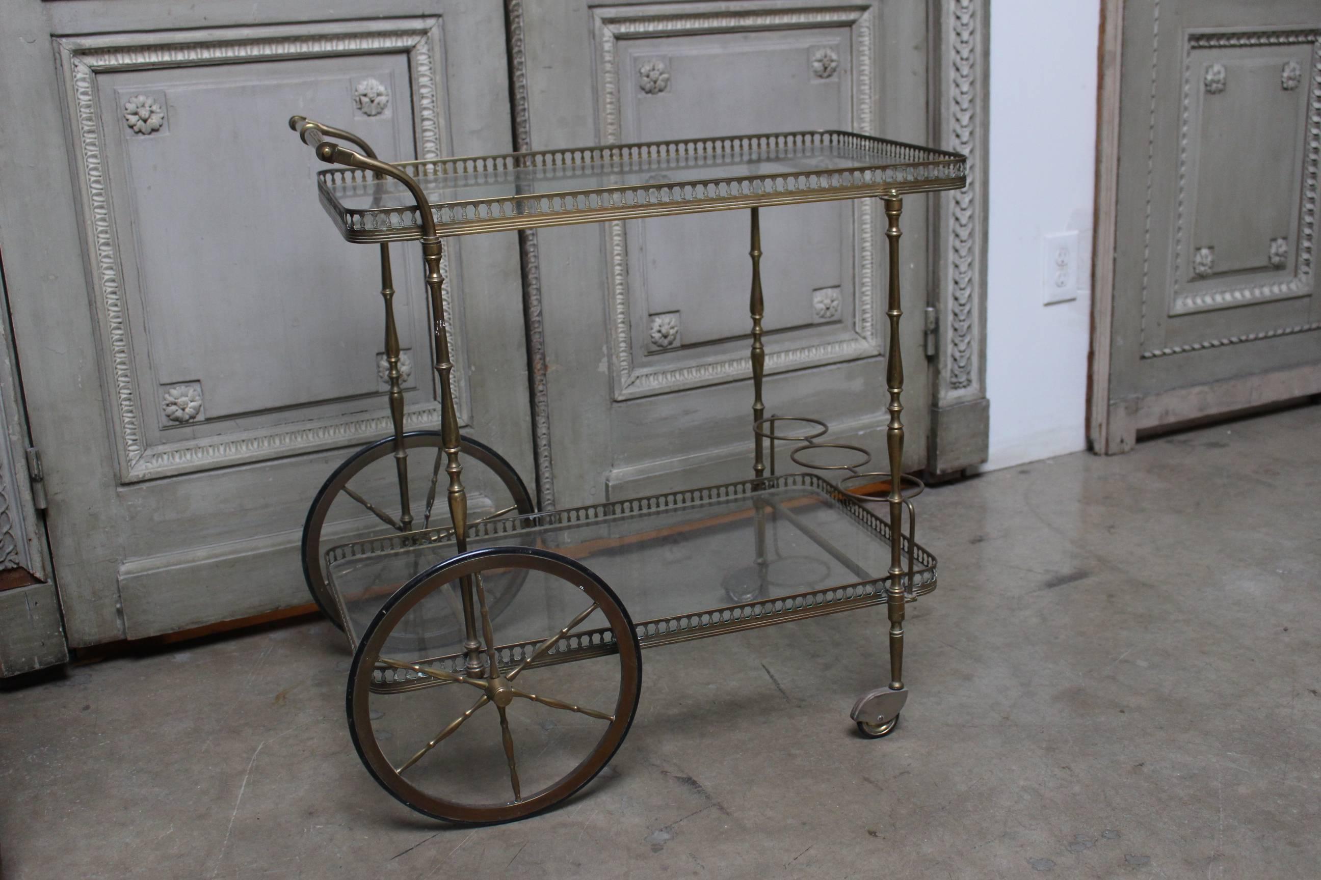 An English brass and glass bar cart with rubber wheels dating from the early 20th century.  It is very sturdy and useful and is highly decorative.  

