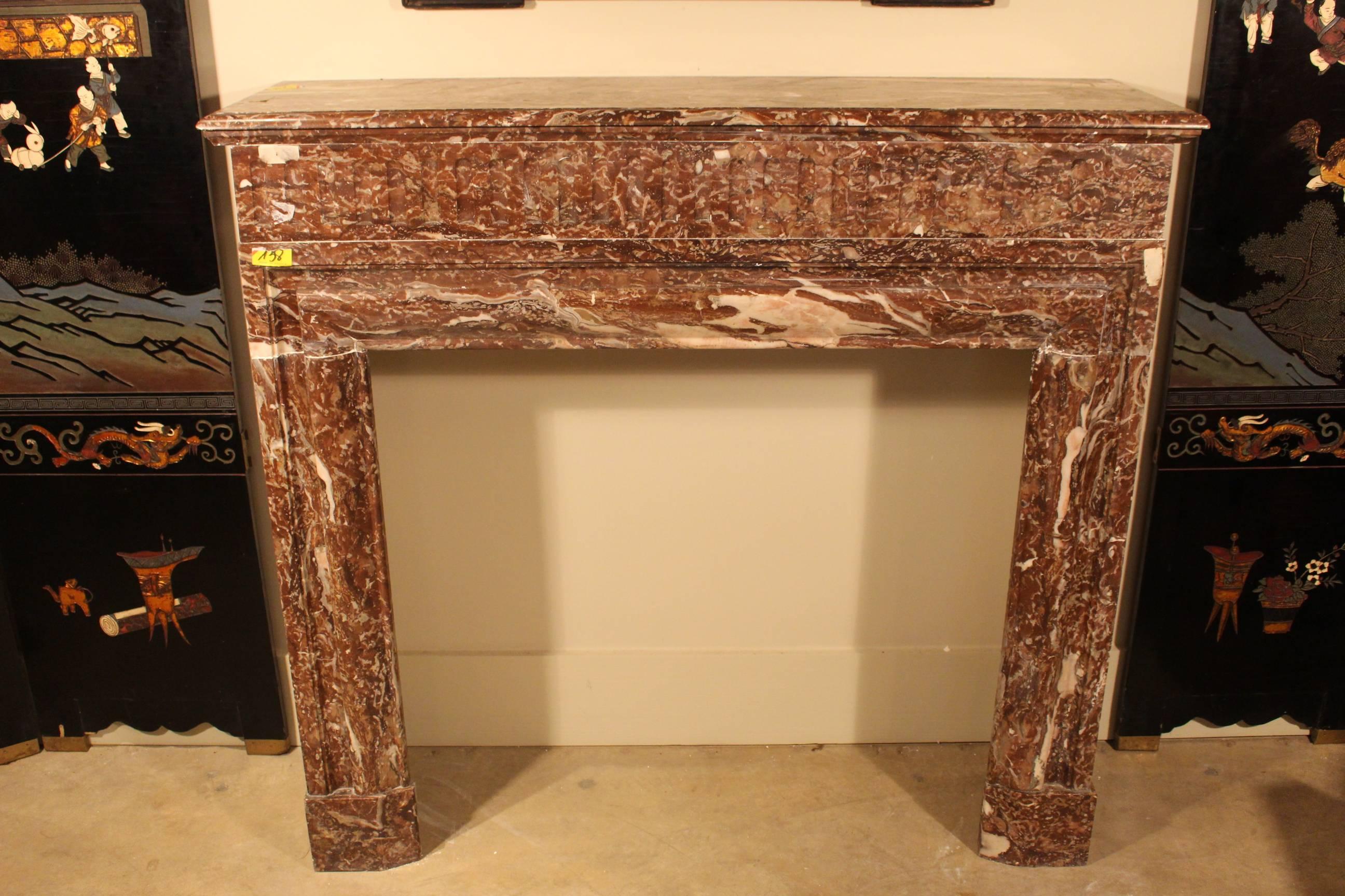 A French Louis XIV style red marble fireplace mantel. The mantel is a great size with neoclassical elements of the Baroque period. The shelf is very deep allowing for large object to be placed on top. The marble is a soft red color with cream and