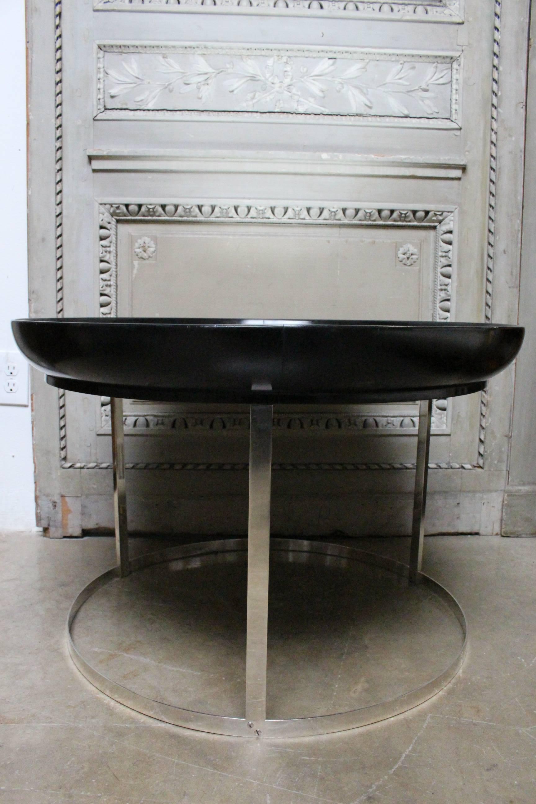 A French round modern cocktail table with a silvered base and lacquered and mirrored top.