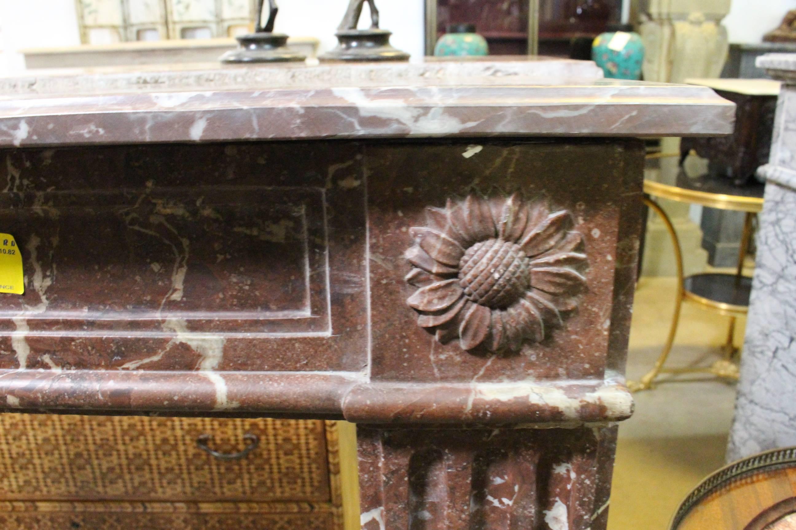 A French Louis XVI style marble mantel with a sunflower motif.