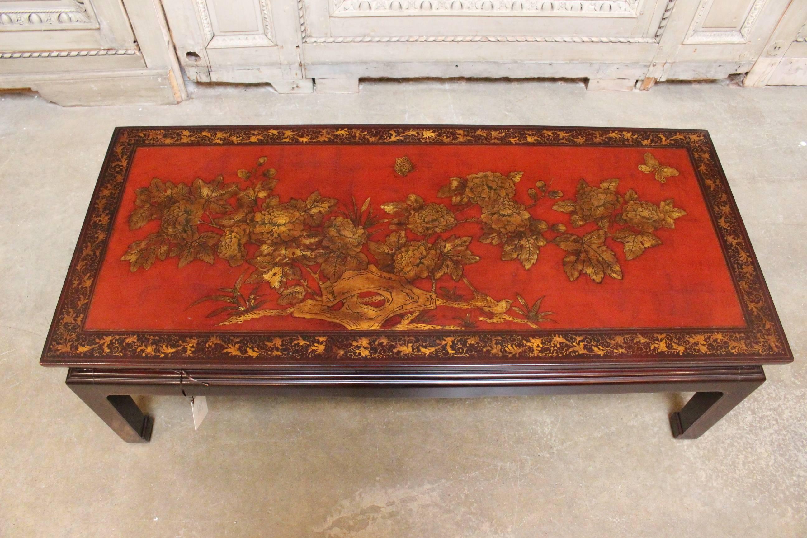 A French chinoiserie style cocktail table with a red and gold lacquered top.
       