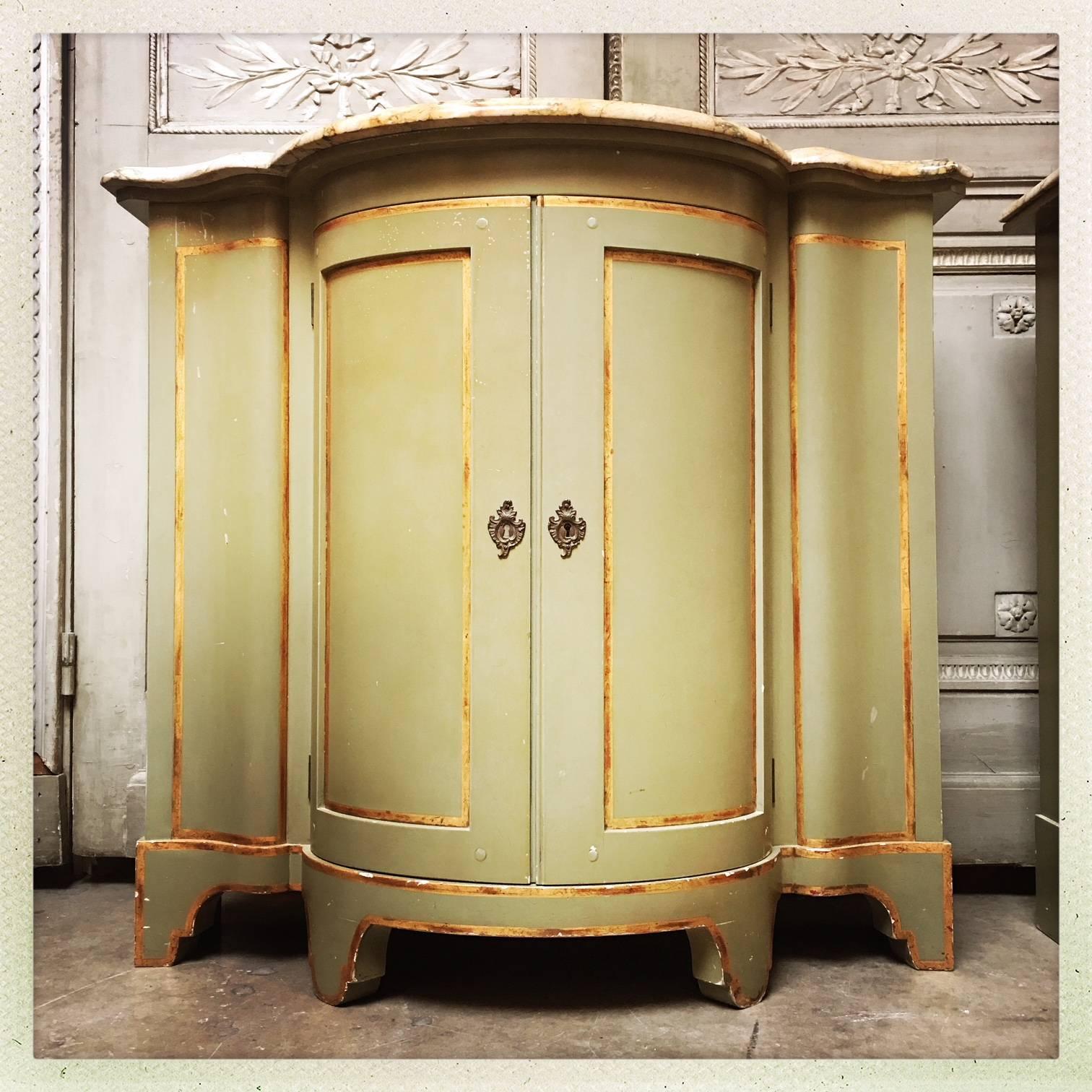 A pair of painted and parcel gilt cabinets with marble tops, by Baker Furniture. 