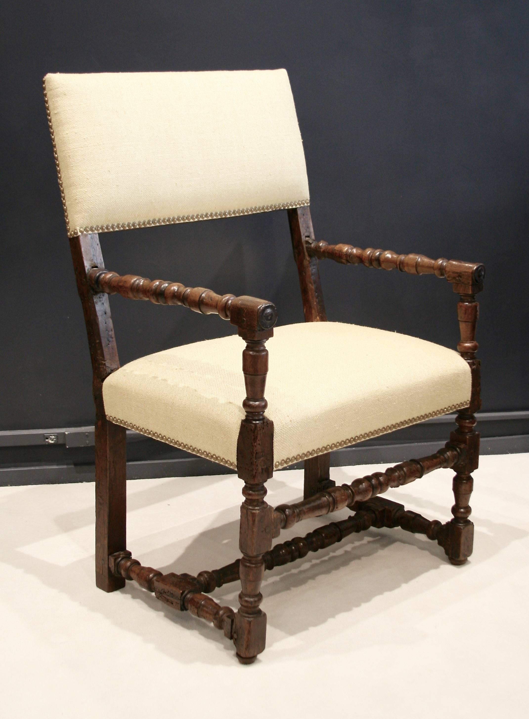 A pair of very rare Flemish early 17th century armchairs. Padded back
and seat (restored) covered with a hopsack weave raw silk in pale cream
color and finished with antique brass nailhead trim.
The chairs have experienced some wurming which