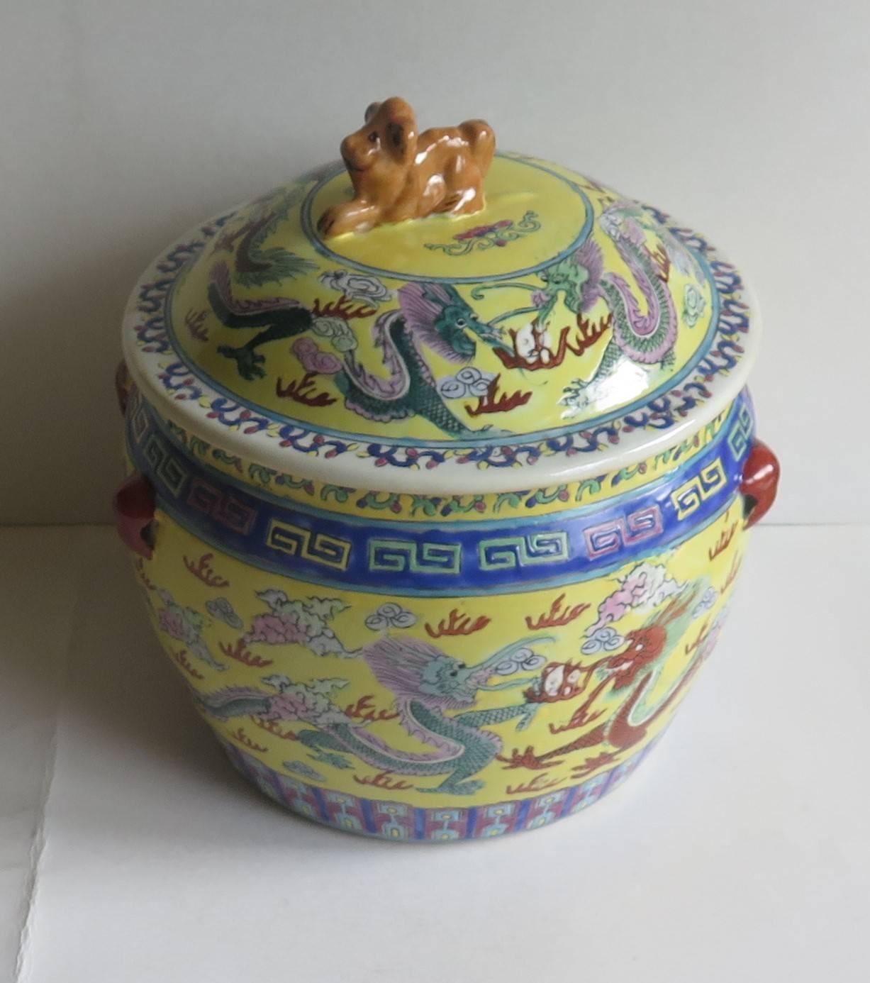 This is a good porcelain, Chinese export, lidded circular pot or bowl, the lid having a nice lion or dog finial.

The decoration is hand-painted on a yellow ground with the main design being five toed dragons chasing flaming pearls among cloud