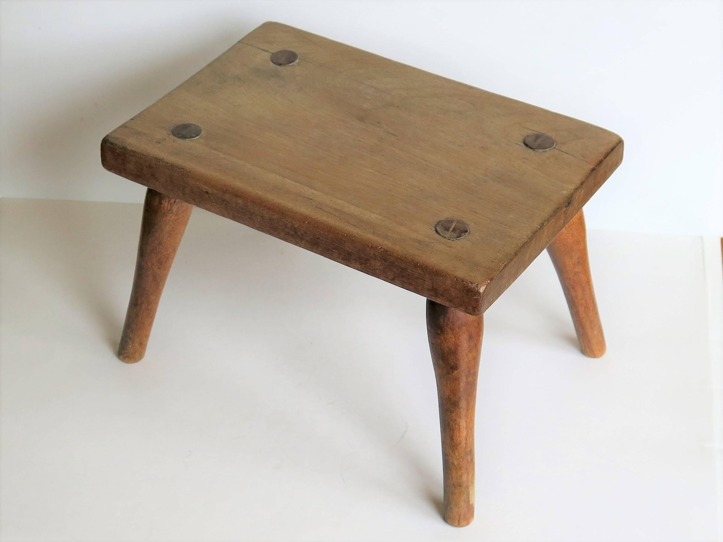 This is an English country foot stool or candle stand from the early 19th century.

The top is made from a single piece of ash and the four splayed turned legs are made of beech. Each leg is tapered forming a tenon, which is morticed through the top