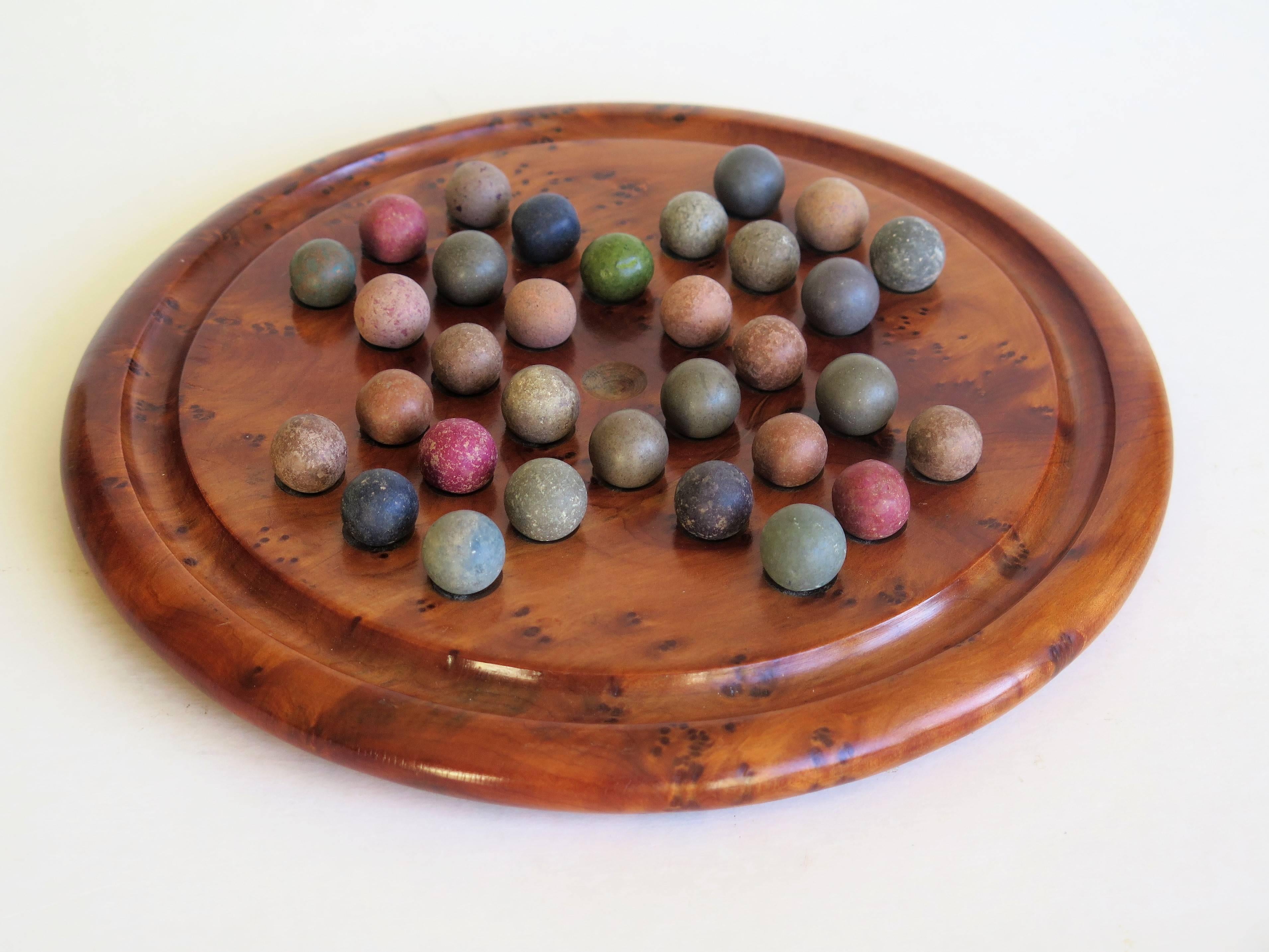 This is a complete Board Game of Marble Solitaire from the late 19th century. 

The circular turned board is very attractive being made of a burr wood, possibly Maple, with a gallery to the outer perimeter. The board has 32 equi-spaced holes with an