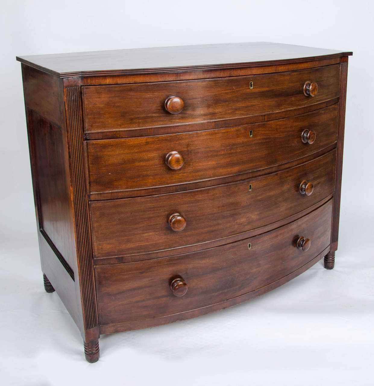 This is a fine Regency, late Georgian period, chest of drawers, with many quality features.

The chest is bow fronted with inset panelled sides, all made of a hardwood, possibly red walnut. The sides of the front are vertically reeded with further