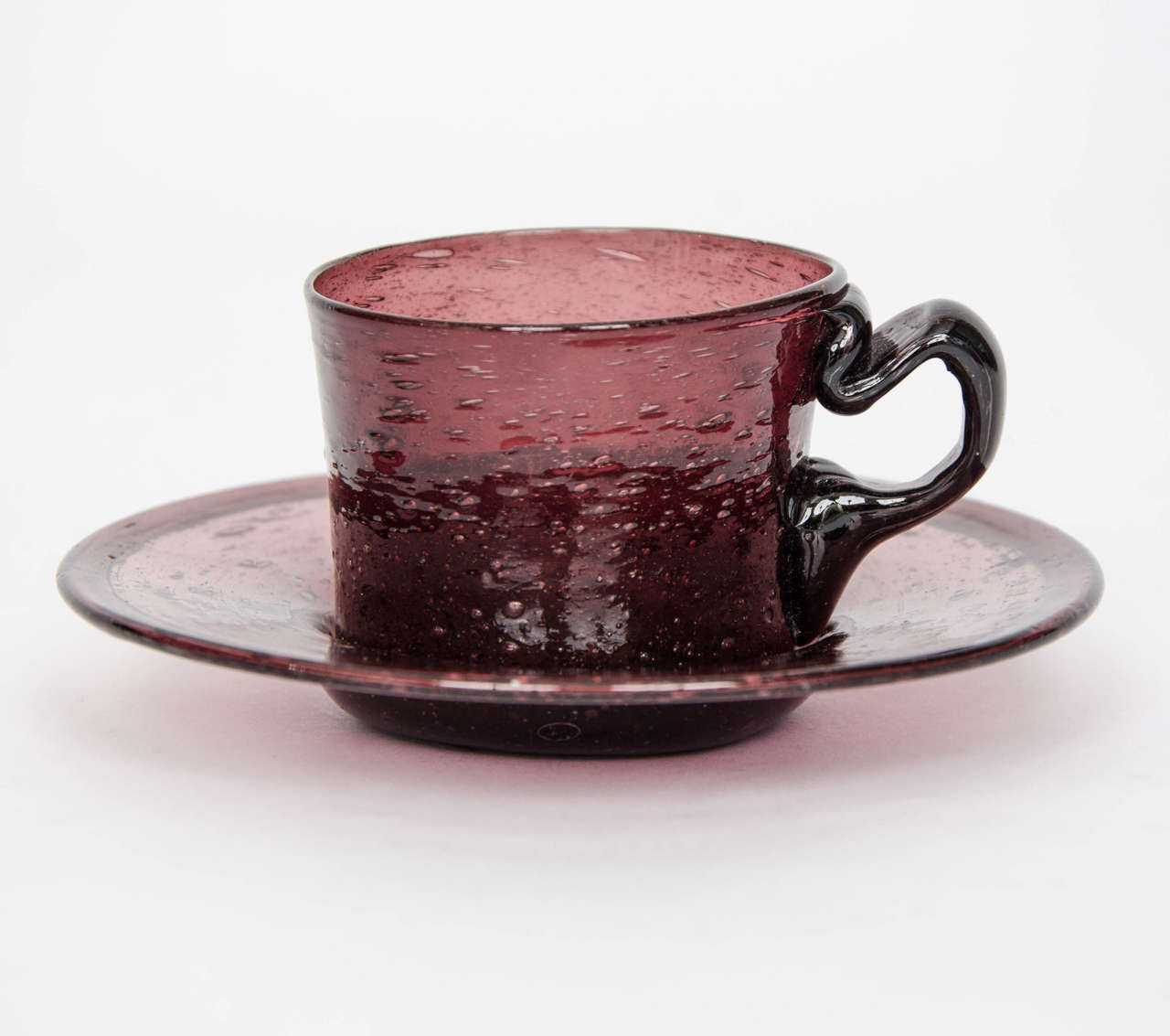 This is a hand blown, glass, cup and saucer made from an amethyst colored glass and dating to the English Georgian period, circa 1800.

Georgian glass cups and saucers are unusual and hard to find.

This one is particularly attractive being made