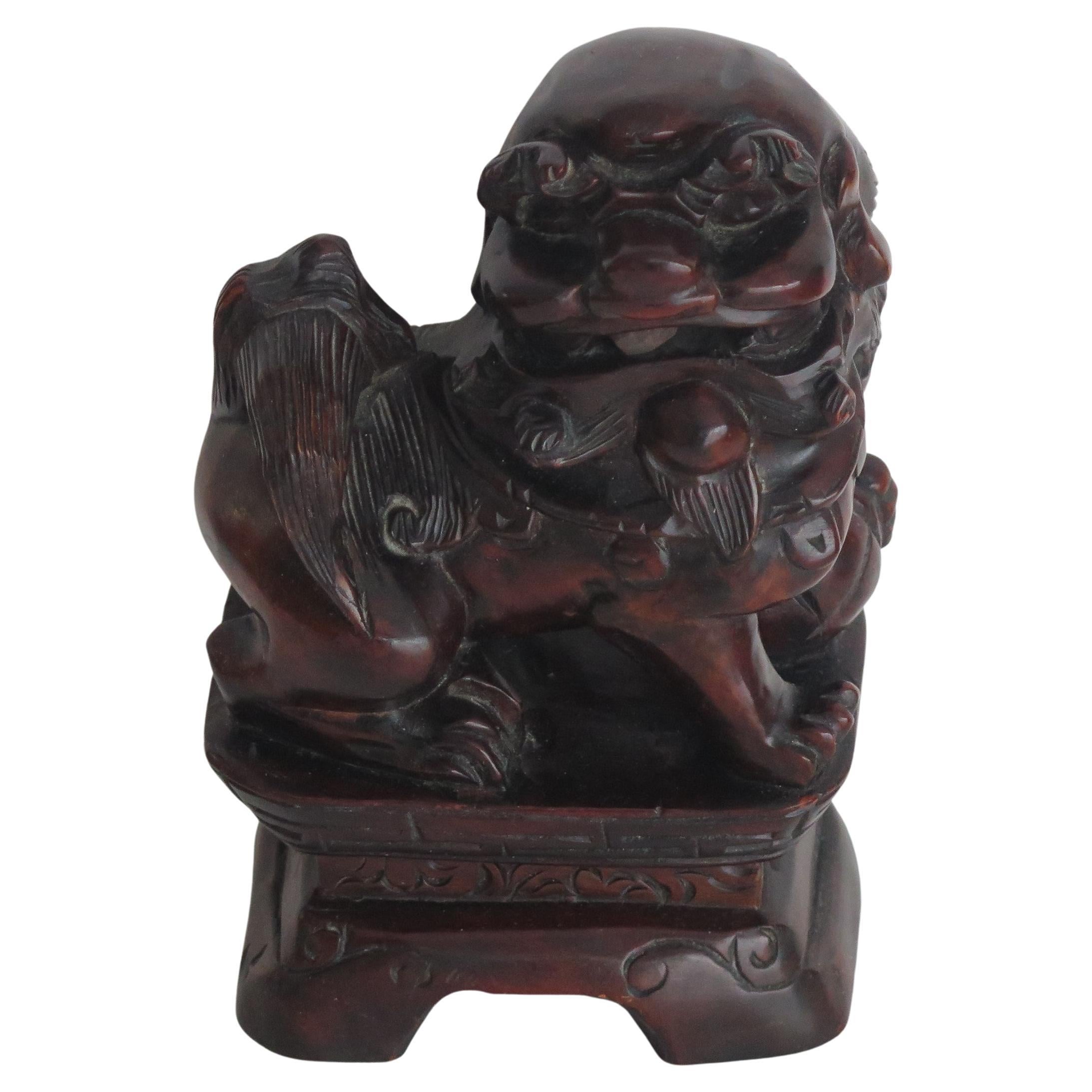This is a good Chinese hardwood foo dog, sometimes called a temple lion that we date to the late Qing period, circa 1900.

The piece is hand carved as a fierce dog or lion sat on a rectangular plinth, with a brocade ball under its paw. 

The