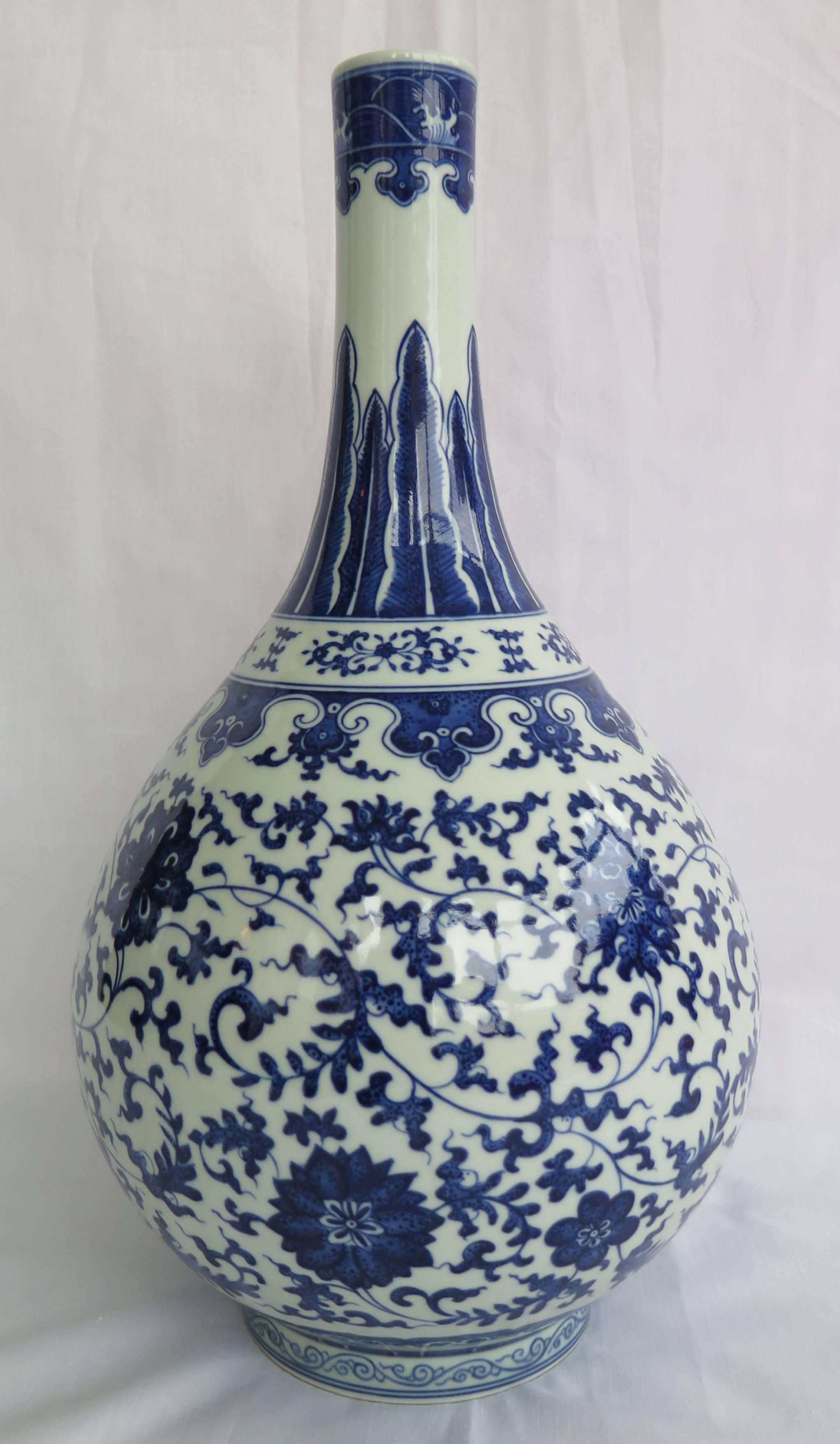 Élégant vase bouteille en porcelaine de Chine reposant sur une base à pieds

Le vase est bien peint dans des tons profonds de bleu cobalt autour du corps avec un grand rinceau de fleurs composées:: dont le lotus:: la pivoine et le chrysanthème::