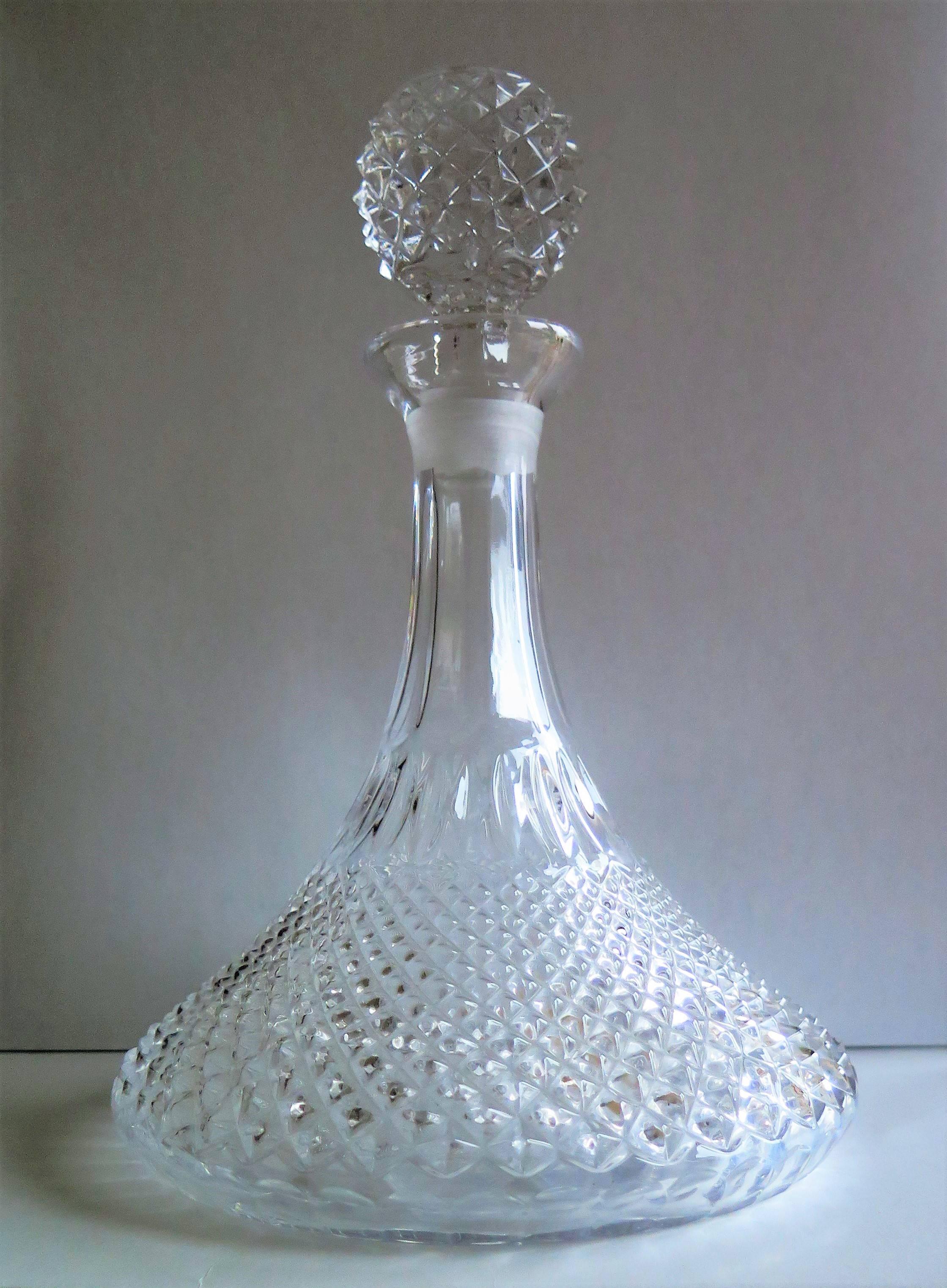 This is a Ship's Decanter with a wide base made from heavy crystal or cut glass having a soft light grey colour.

The decanter is diamond cut to its lower half with the diamonds graduating from the base, getting smaller towards the centre, below