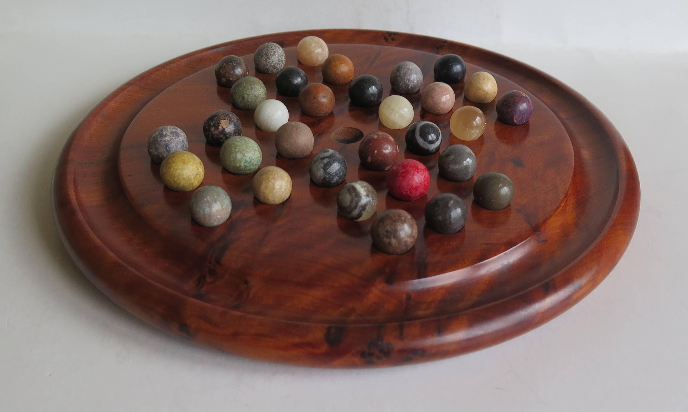 This is a complete Game of Marble Solitaire from the late 19th Century. 

The circular turned board is very attractive being made of Burr Walnut, with a gallery to the outer perimeter. The board has 32 equi-spaced holes with an additional central