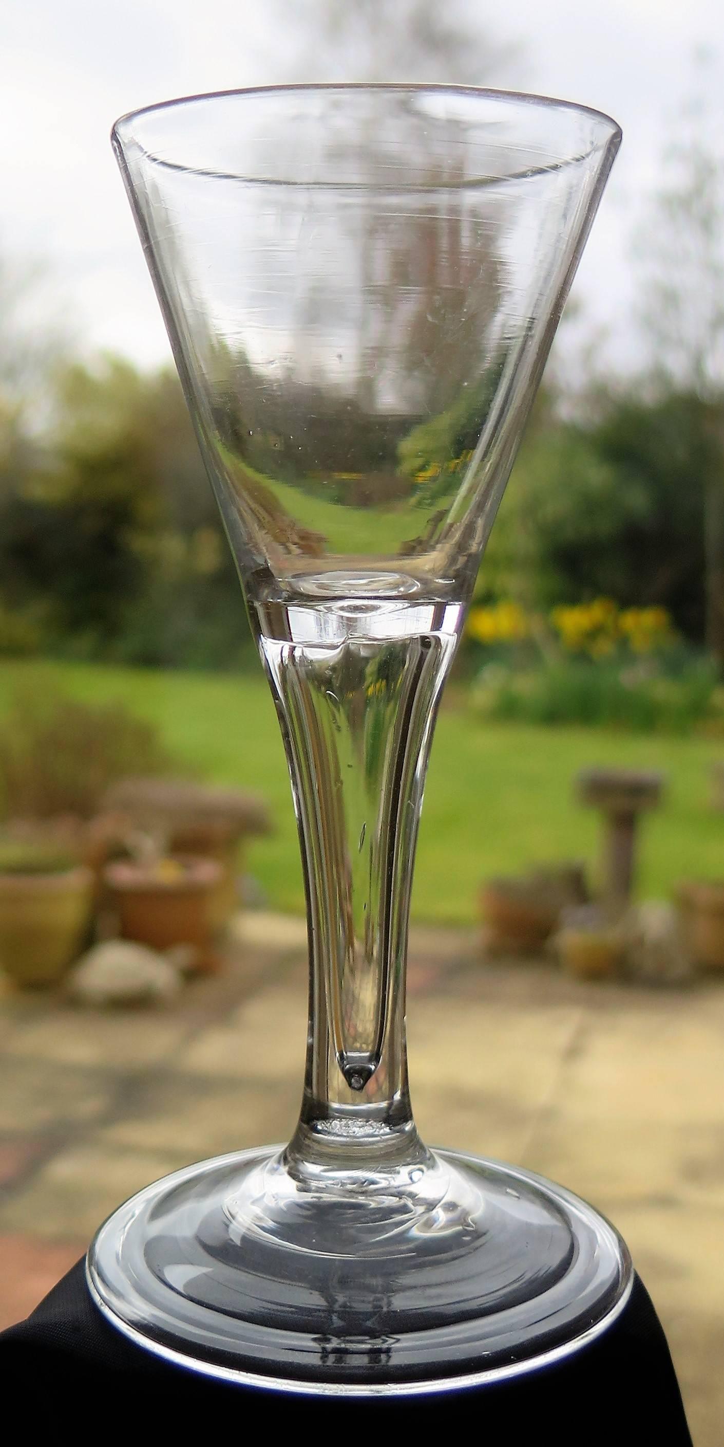 This is a rare English, Georgian, wine glass, dating to the George II Period of the mid-18th century, circa 1750. These glasses are very collectible. This wine glass is handblown from English lead glass and has a soft grey color.

The glass has a