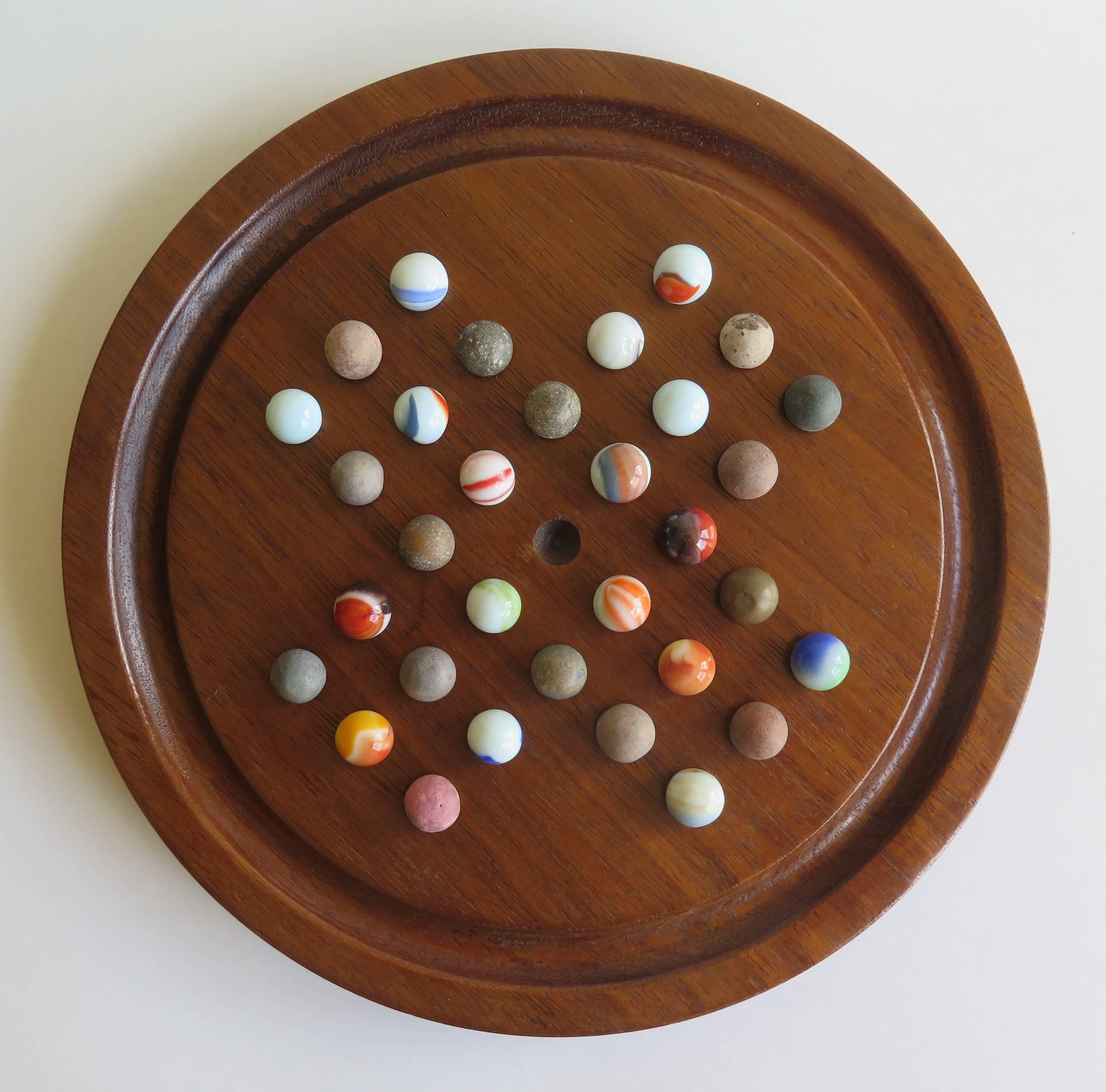This is an original and complete game of marble solitaire from the late 19th century. The circular turned board is made of oak and sits on a low foot with later green baize to the base.

The board has 32 equi-spaced holes with an additional one in