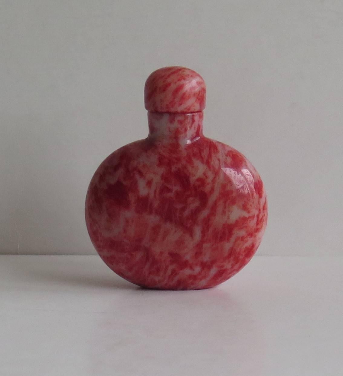 This is a good and very decorative Chinese snuff bottle from the mid-20th century, circa 1940.

The bottle is made of a hand-carved and polished natural hard-stone, possibly thulite. The stone has an excellent natural mottled texture with colours of
