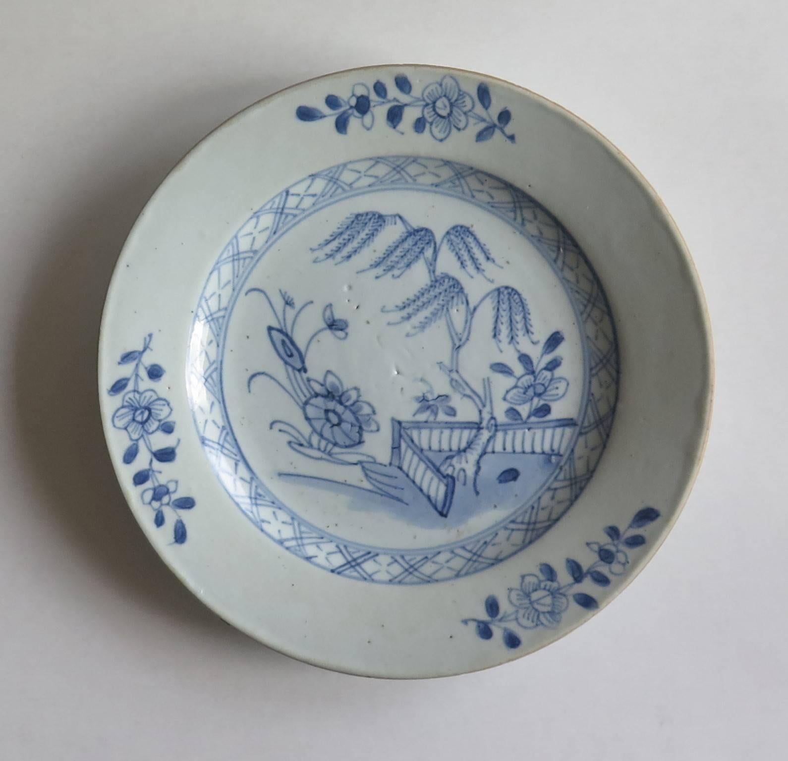 This is a Chinese porcelain blue and white side plate which we date to the mid-18th century or possibly earlier.

The plate is hand-painted in a free-flowing style with varying shades of cobalt blue. The decoration features a willow tree and other
