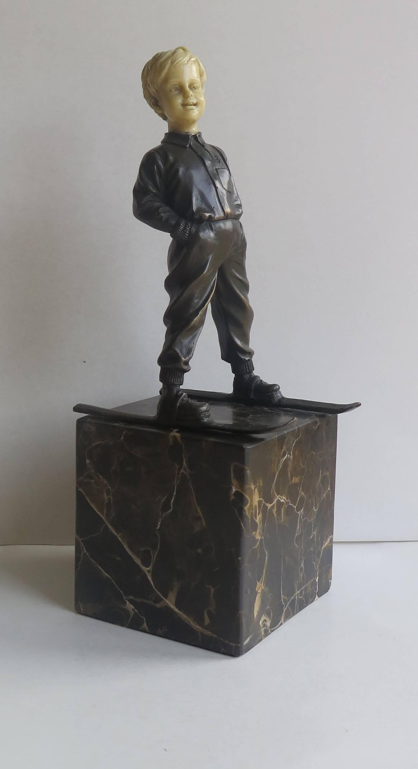 This is a good quality, figurative metal sculpture. 

This Art Deco style figurine depicts a boy wearing ski’s stood with his hands in his pockets. The figure is made of bronze or spelter ( probably bronze) with the nicely detailed head made of