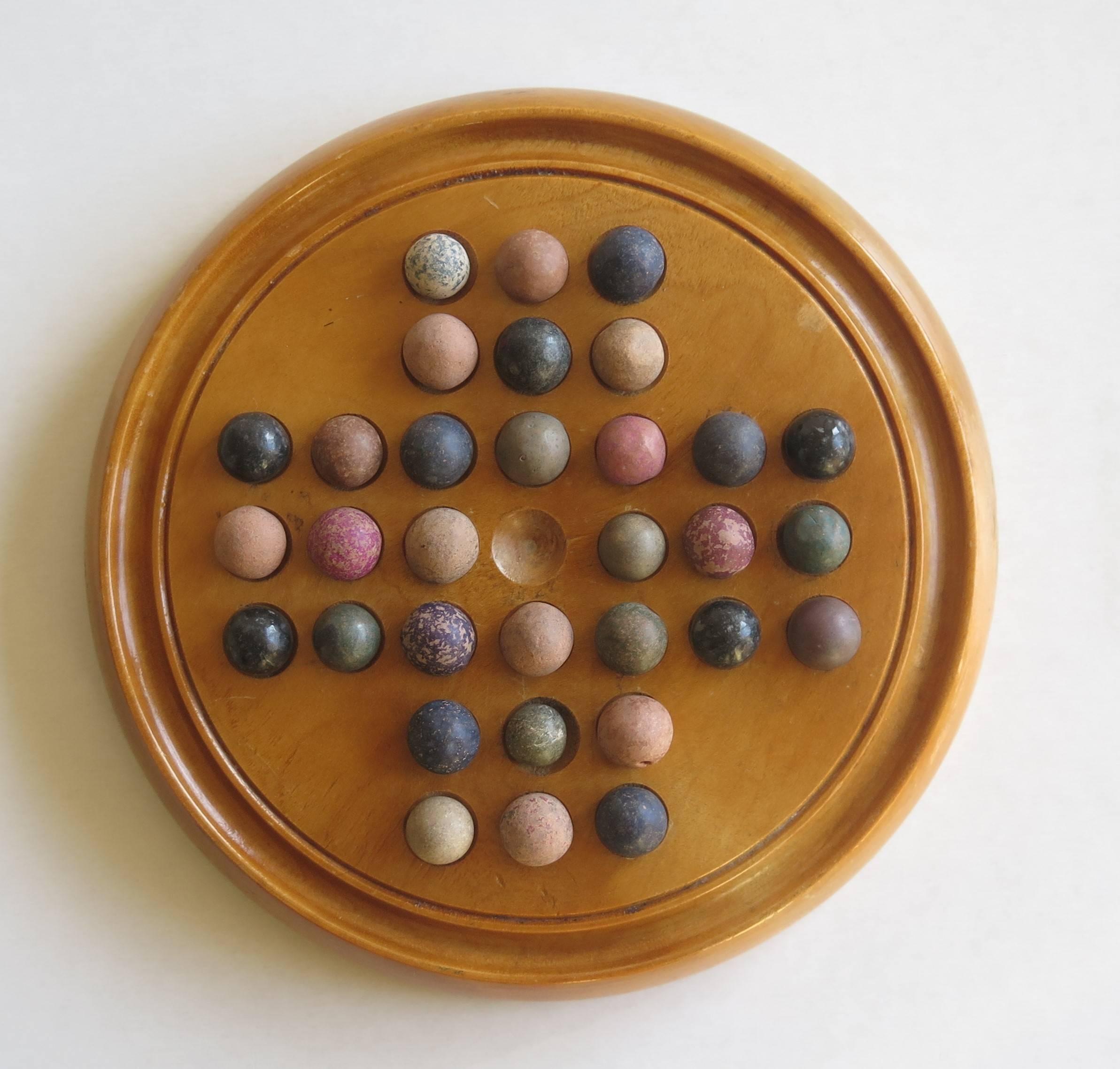 This is an original and complete game of marble solitaire from the late 19th century.

The circular turned board is made of a light coloured hardwood. The board has 32 equi-spaced holes with an additional one in the centre and a gallery to the outer