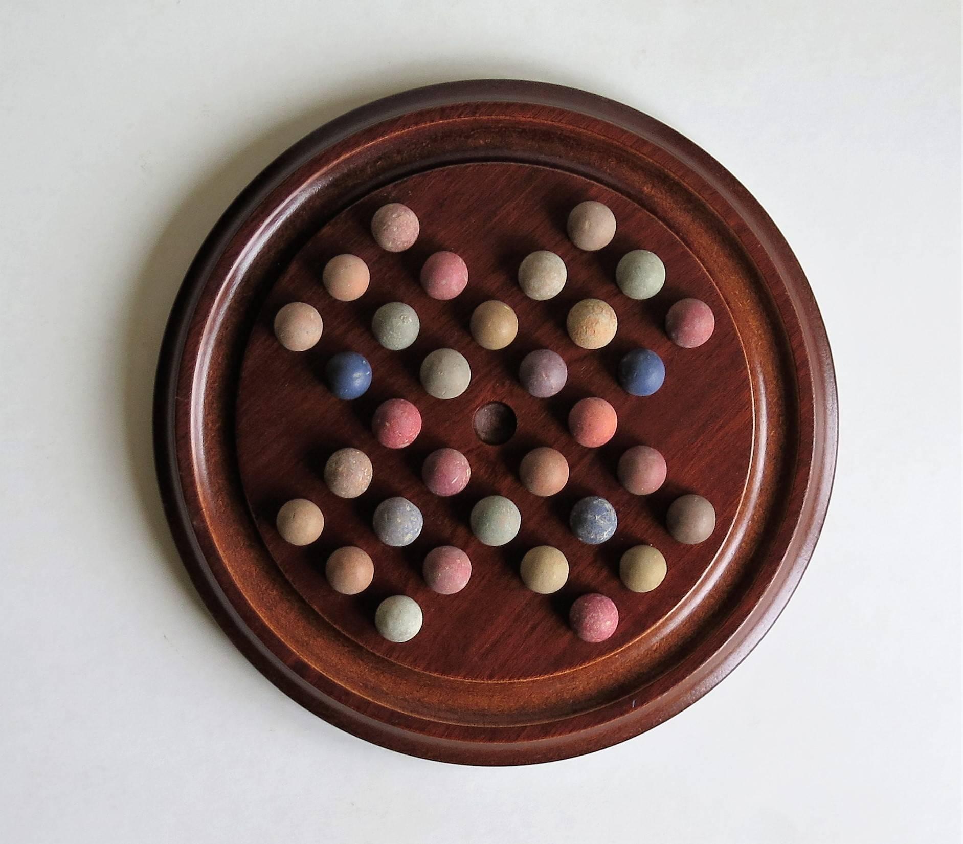 This is a table sized game of marble solitaire, having a very good board and a complete set of early marbles. 

The circular turned board is made of mahogany and has an excellent grain and color. The board has 32 equi-spaced holes with an additional