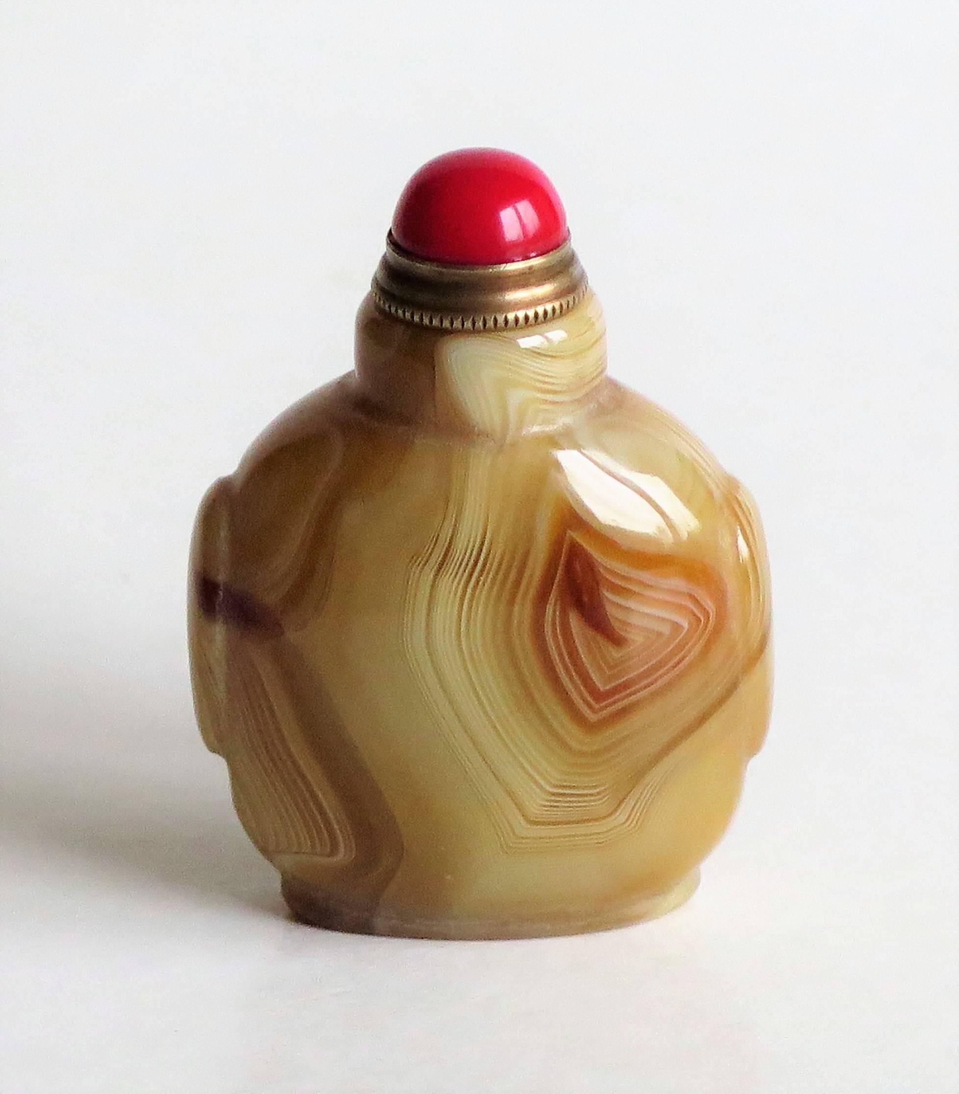 This is a beautiful Chinese snuff bottle.

The striking bottle is hand-carved from natural agate which has superb veined detail within the stone, with a lovely shade of colours from a very light cream to a dark ochre brown. The bottle is inside