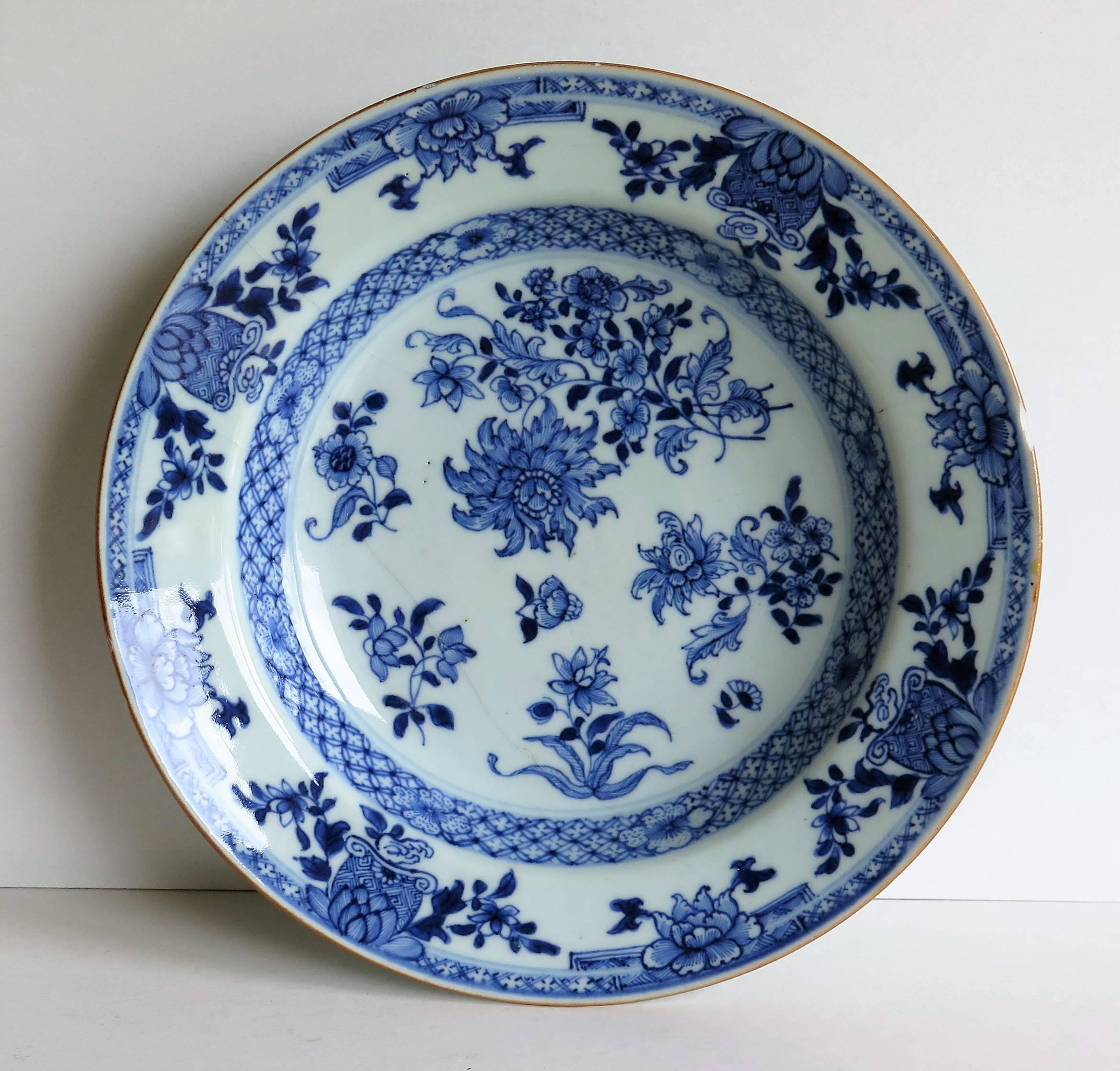 This is a Chinese, Qing dynasty, porcelain, blue and white plate or bowl, from the 18th century, circa 1770.

The plate is circular in shape, decorated in varying shades of cobalt blue, with a glassy glaze of a very light blue shade. The base is