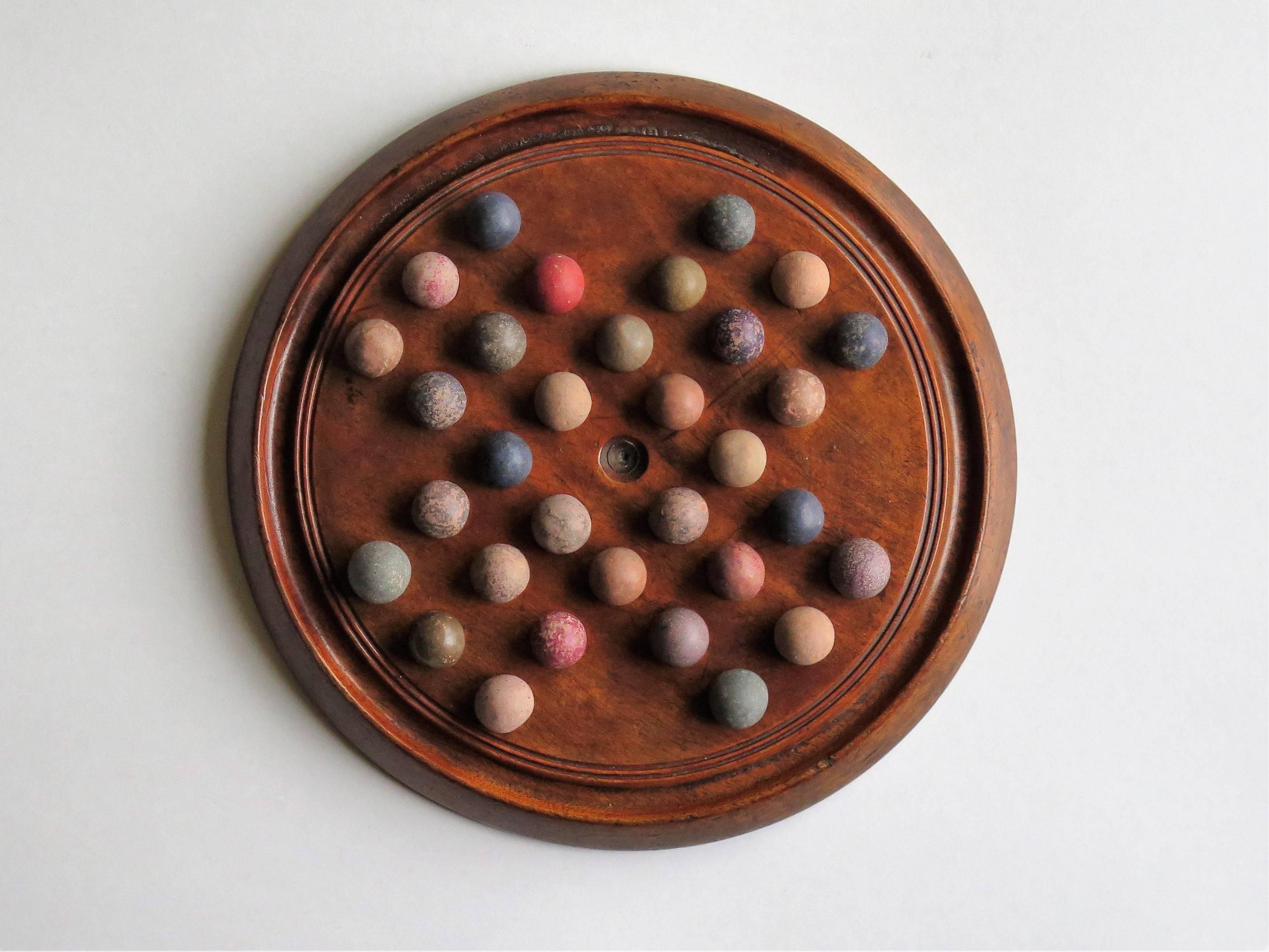 This is an original and complete game of marble solitaire from the mid-19th century or possibly earlier.

The circular turned board is made of mahogany and has developed a lovely color and patina through years of use. The board has 32 equi-spaced