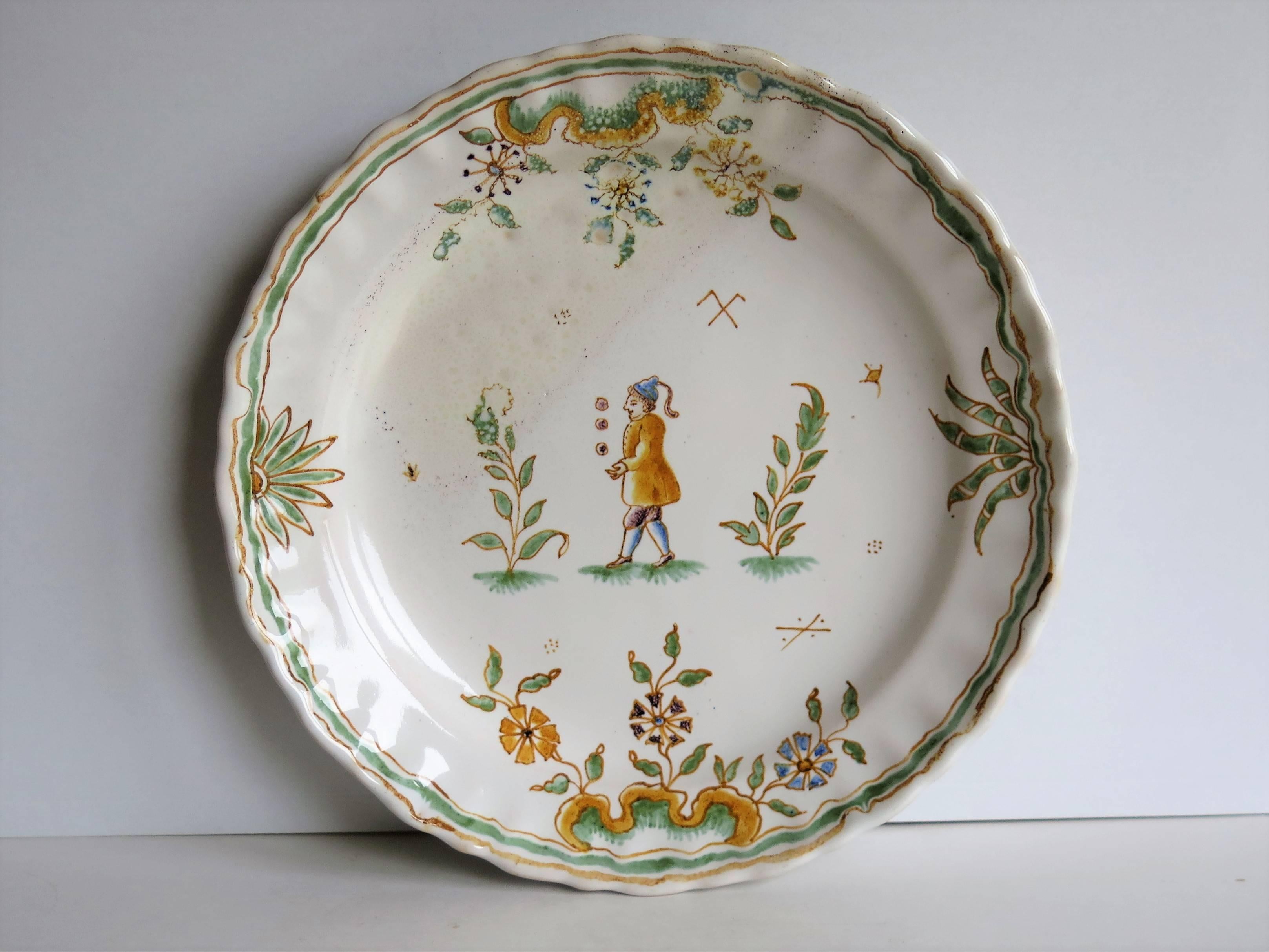 This is a good tin-glazed pottery dish or plate which we attribute to French Faience.

The dish has a wavy edge with no foot rim and is made from a pale buff / grey earthenware.

It is decorated in a simple country style, all hand-painted in a