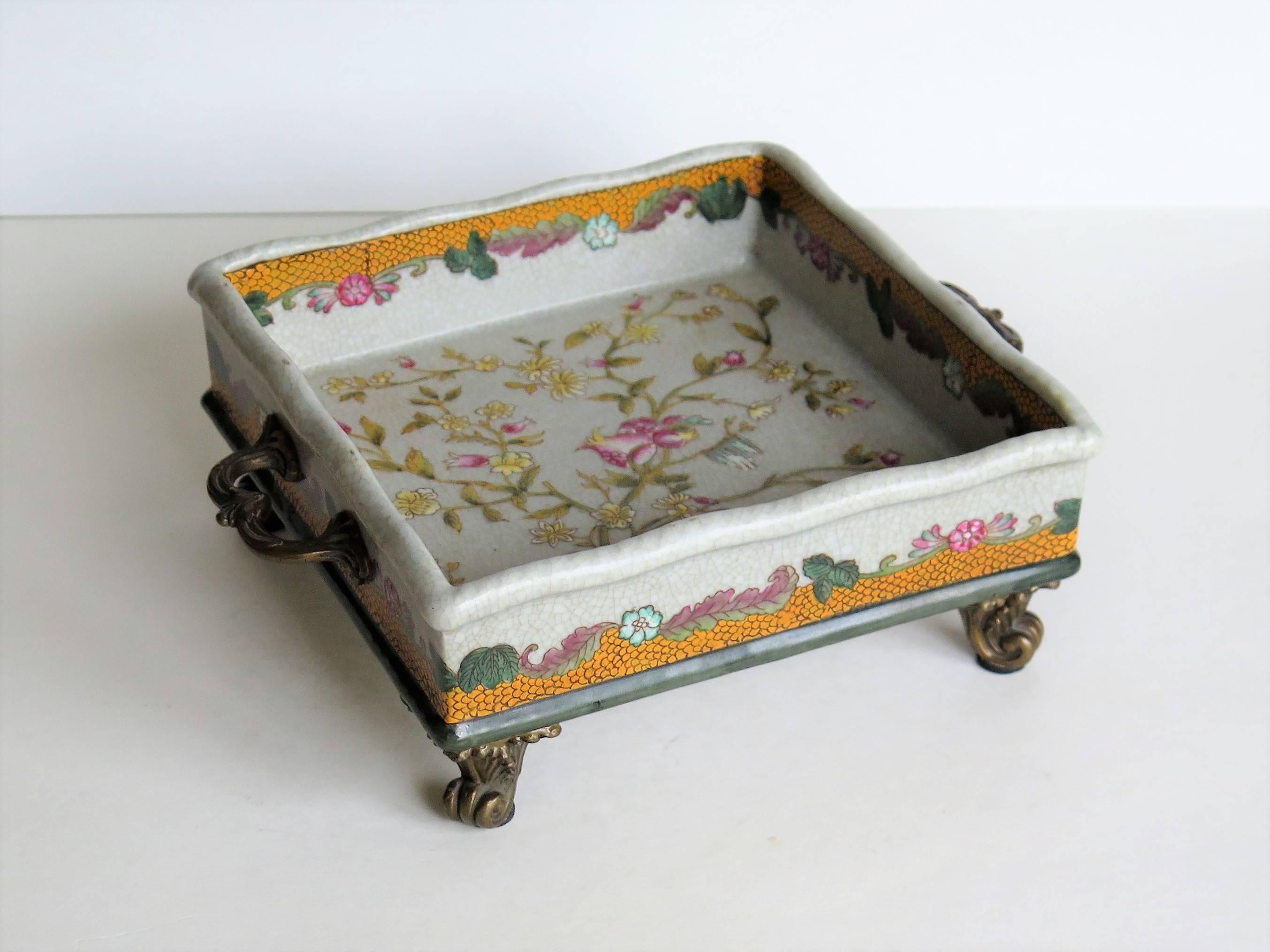 This is a very decorative, Chinese export, ceramic Tray or Dish. 

The dish has a nominally square shape with low sides and two small side handles. It is mounted on four small feet. The ormolu handles and feet are made of cast brass or bronze