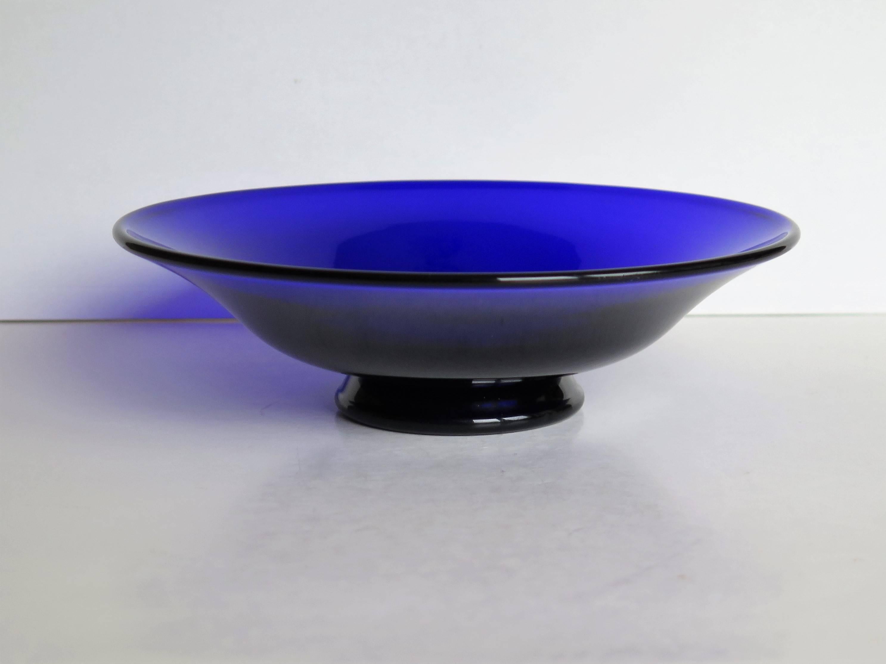 This is a fine quality glass bowl by the glass manufacturer Thomas Webb. 

This circular bowl is made of bristol or cobalt blue and has a lovely curved shape with a flared rim raised on a shaped foot. 

Thomas Webb was an English glassmaker and the