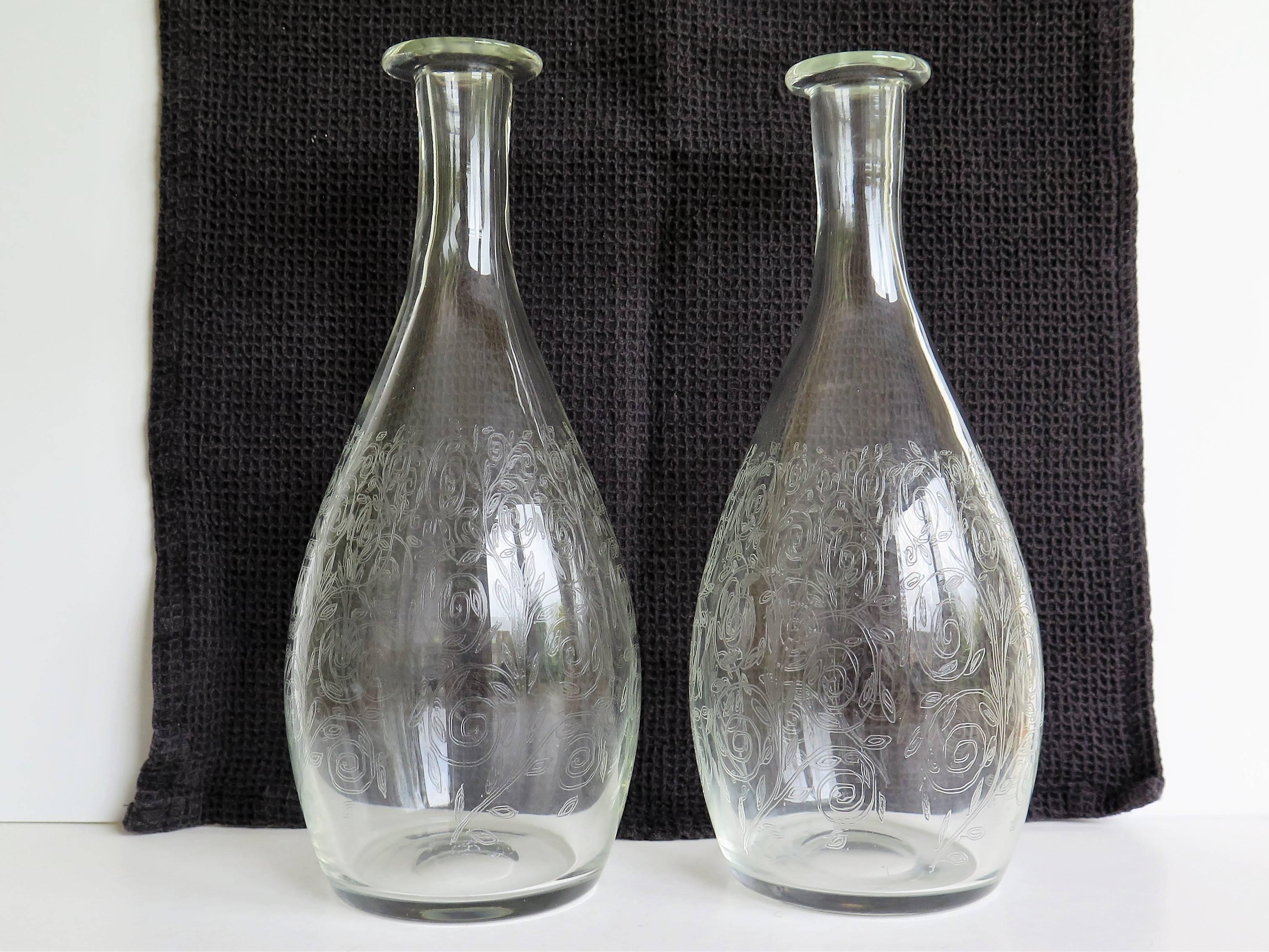These are a fine pair of hand-blown, English, lead glass carafes, jugs, decanters or bottle vases dating to the 19th Century.

The carafes / vases are bottle shaped, tapering to the neck with nicely lipped rims. They have ground out pontil marks to
