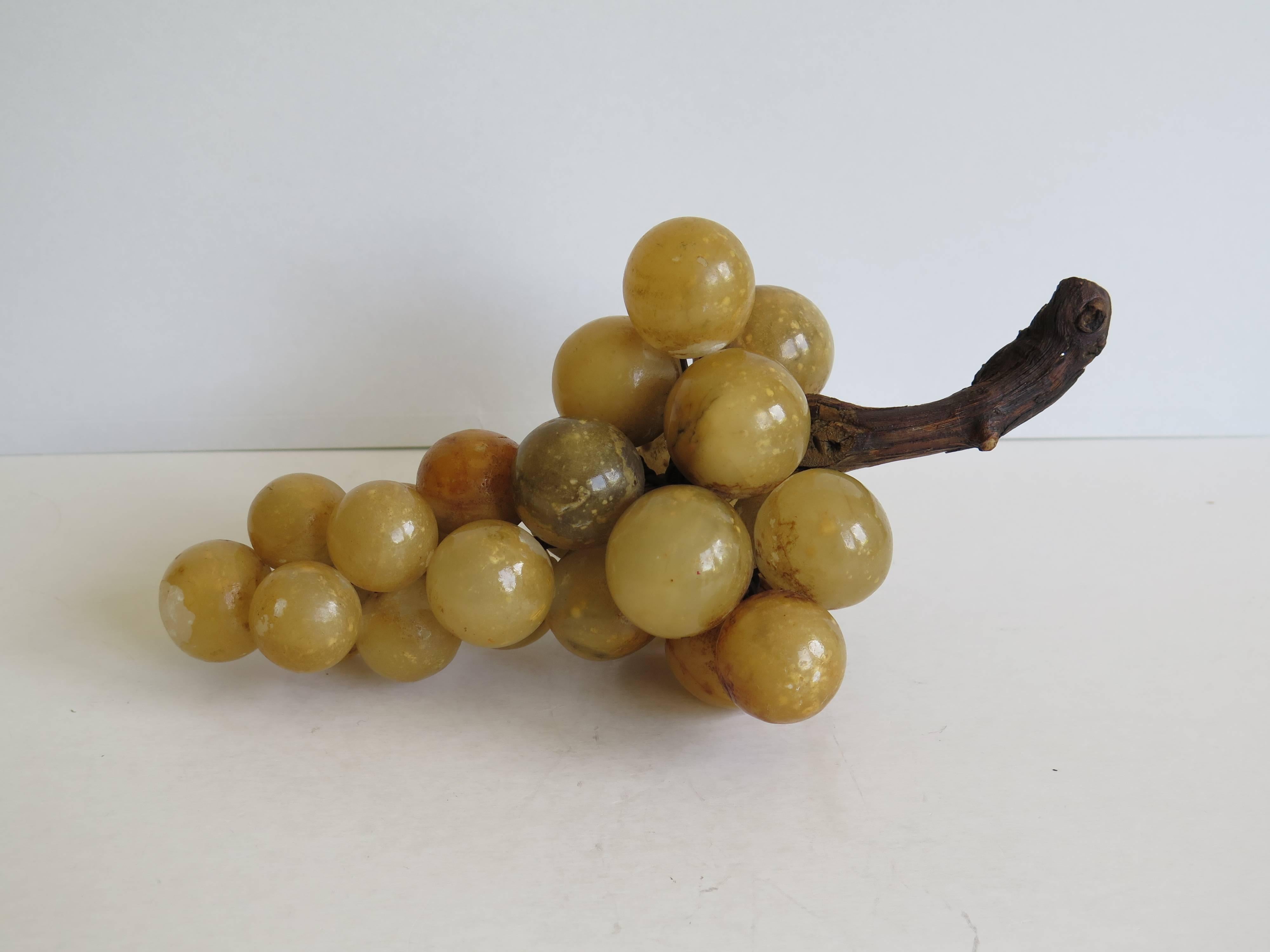 This is a very decorative fruit cluster of hand-carved grapes, made from Alabaster stone, probably from Italy originally.

Each grape is handcrafted, hand-painted / varnished then individually wired to a beautiful twisted natural wood grapevine